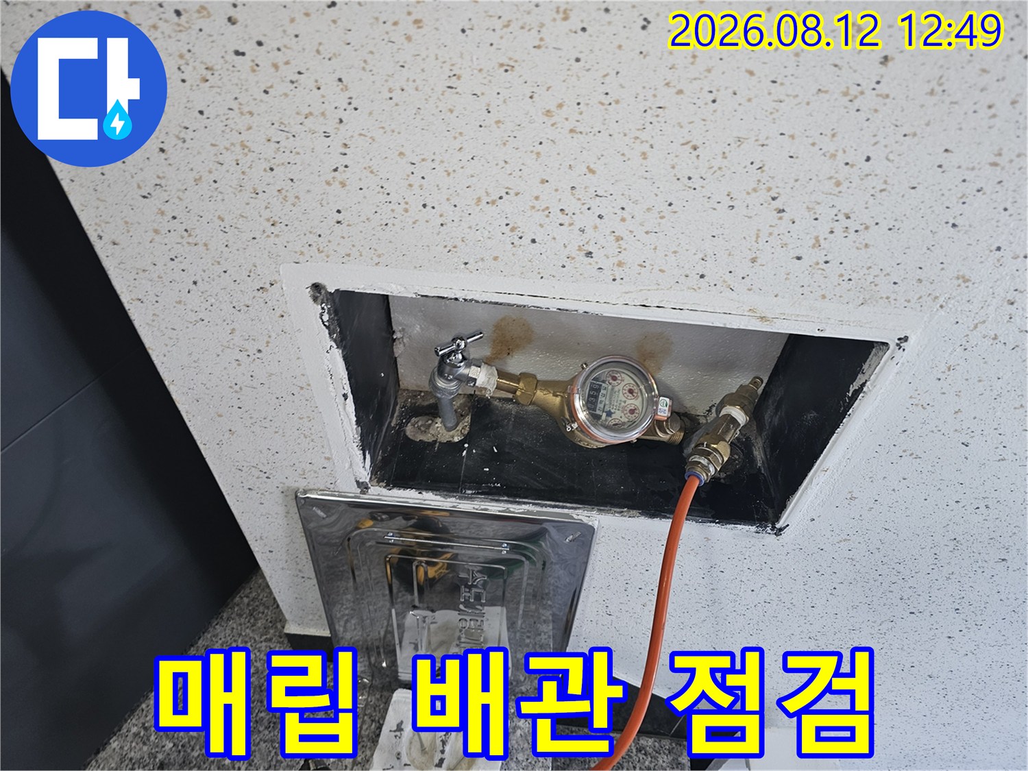 벽면 내부로 노출된 수도 계량기와 압력 측정용 호스 연결 상태