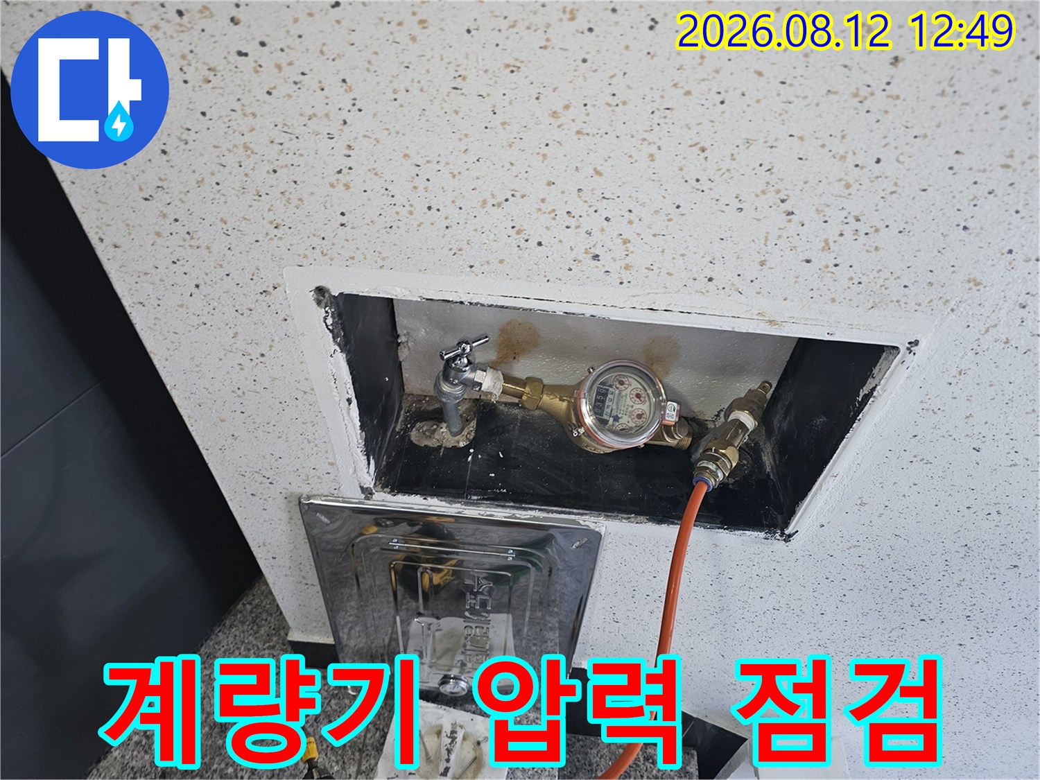 벽면 내부에 위치한 수도 계량기와 연결된 압력 측정 호스