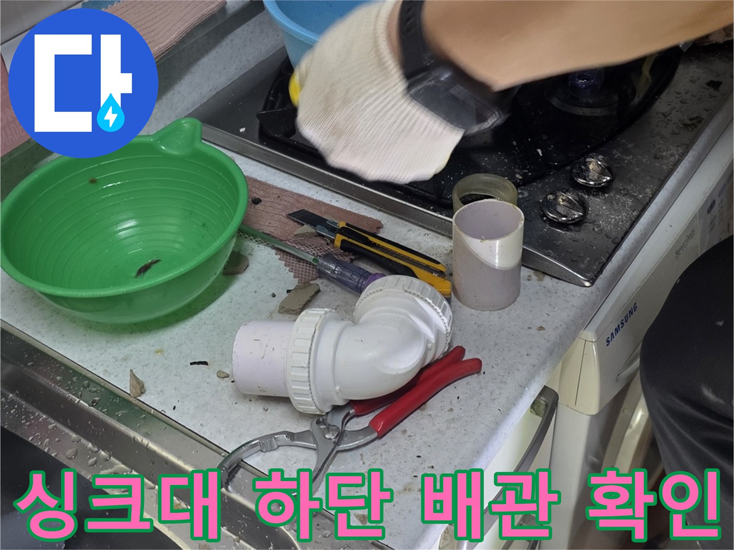싱크대 아래쪽의 백색 배관과 연결 부품을 점검하는 사진입니다.