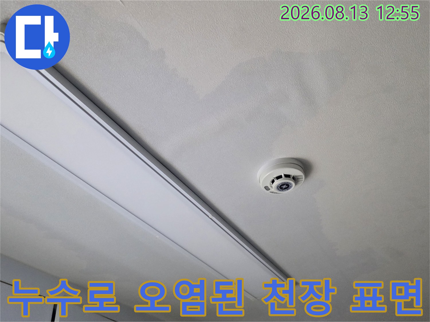 흰색 실내 천장의 누수 얼룩-과 중앙에 설치된 화재 감지기 모습