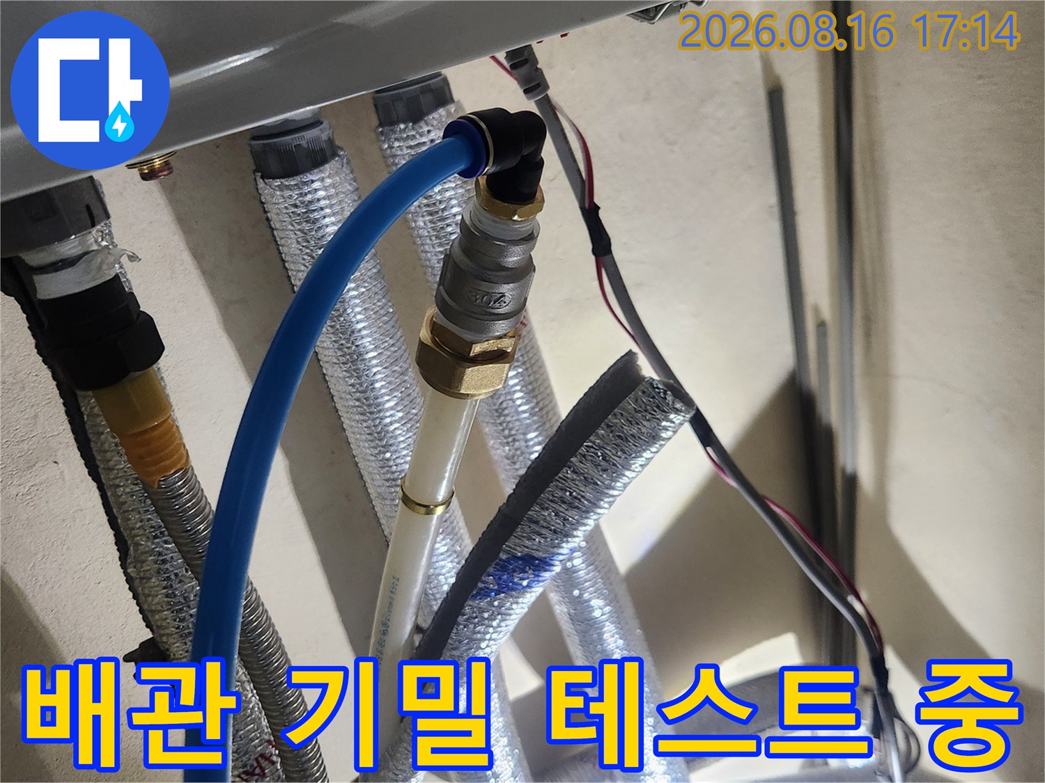 보온재로 덮인 배관 연결부에 압력 게이지를 설치하여 누수를 점검합니다.