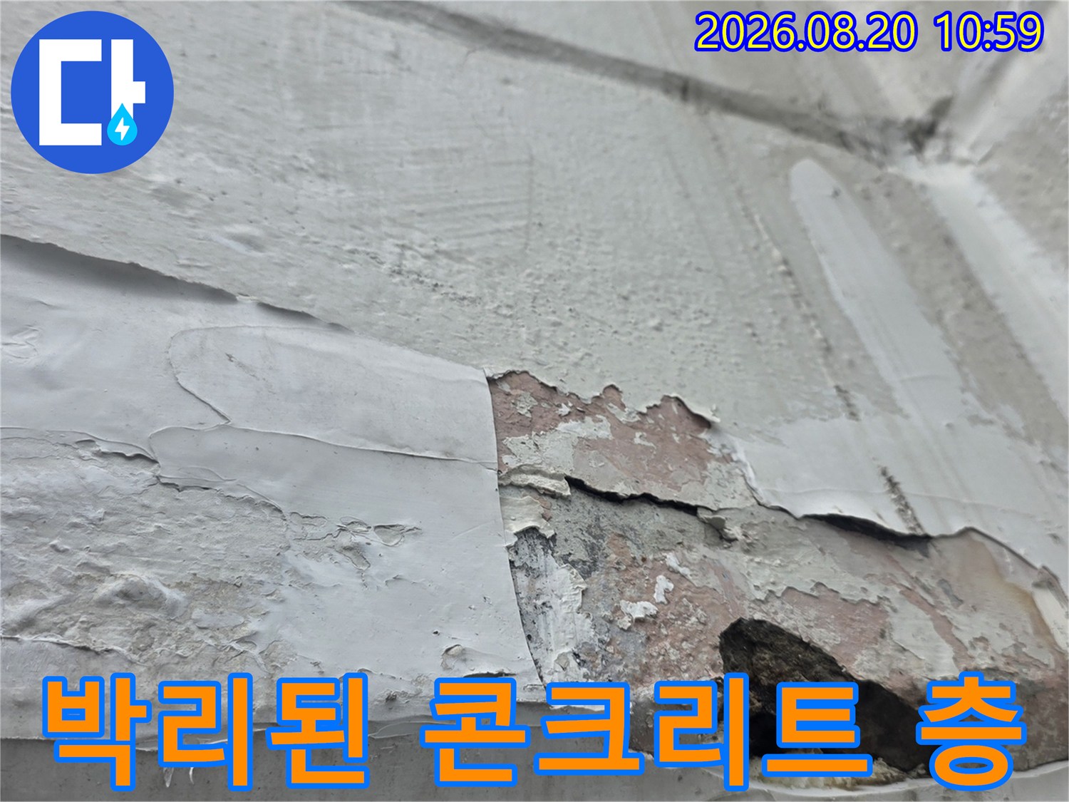 콘크리트 표면이 벗겨져-내부 층이 드러난 외벽 손상 부위 사진입니다.