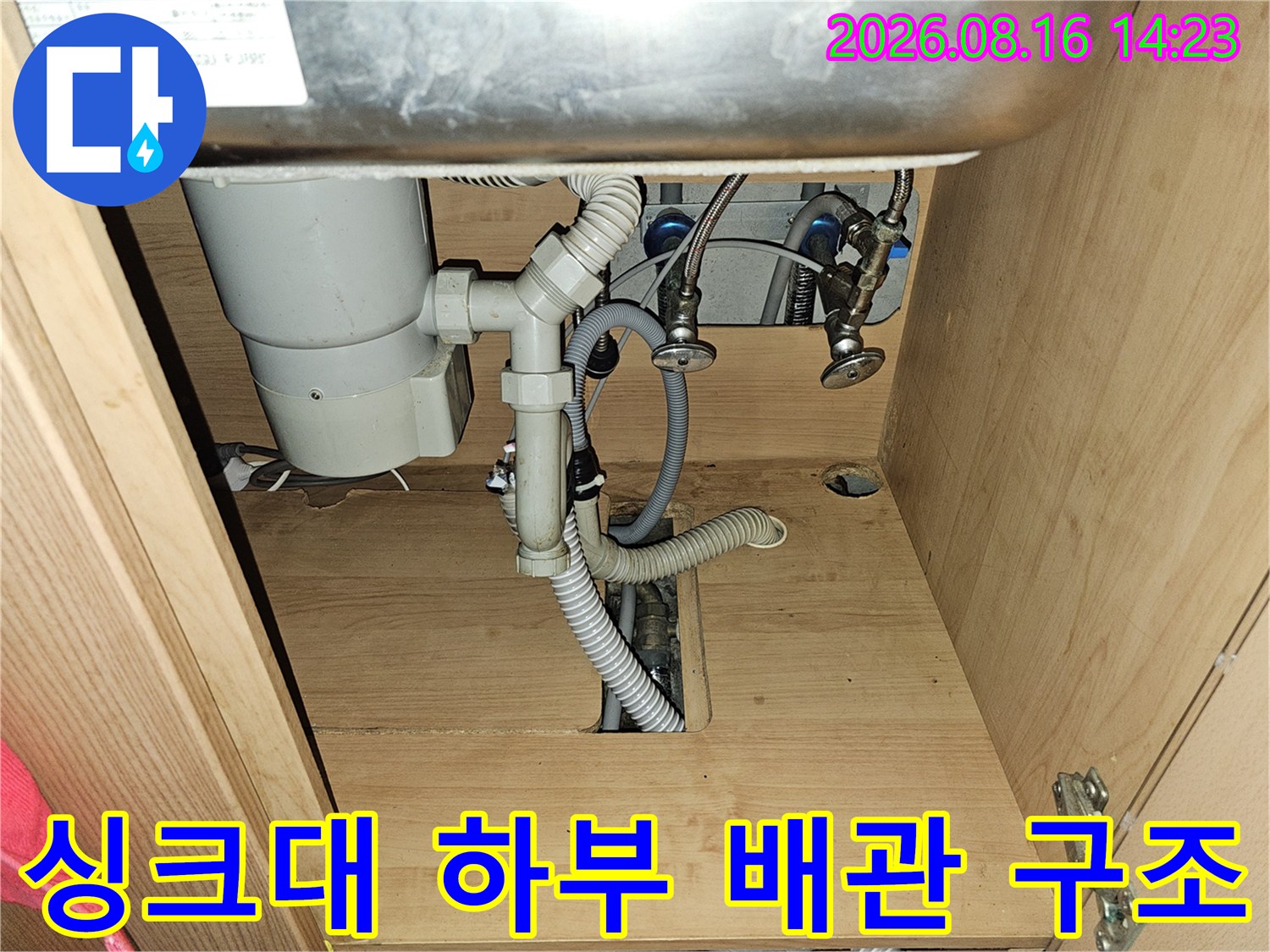 싱크대 아래쪽의 복잡한 호스와 배관 연결 모습