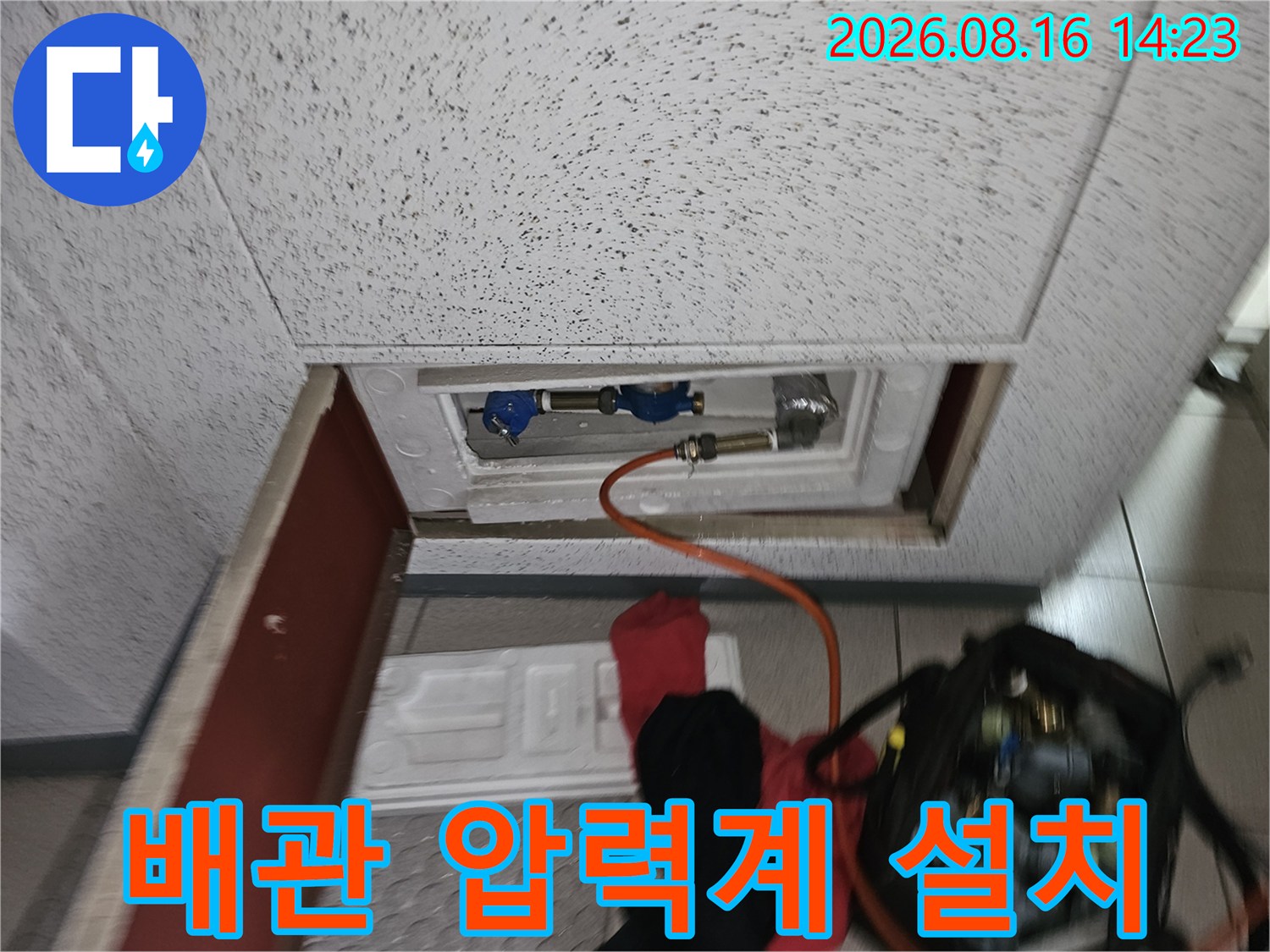 천장 점검구 내부-배관에 연결된 압력 측정 장비와 호스의 모습입니다.