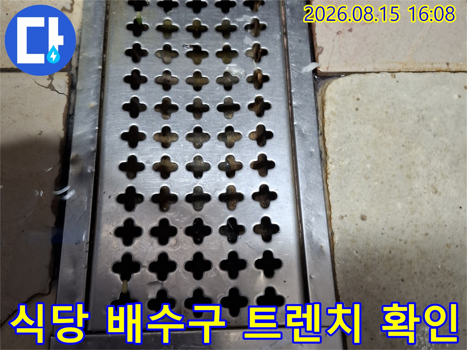 물기가 있는 타일 바닥과 스테인리스 배수 트렌치 구조물