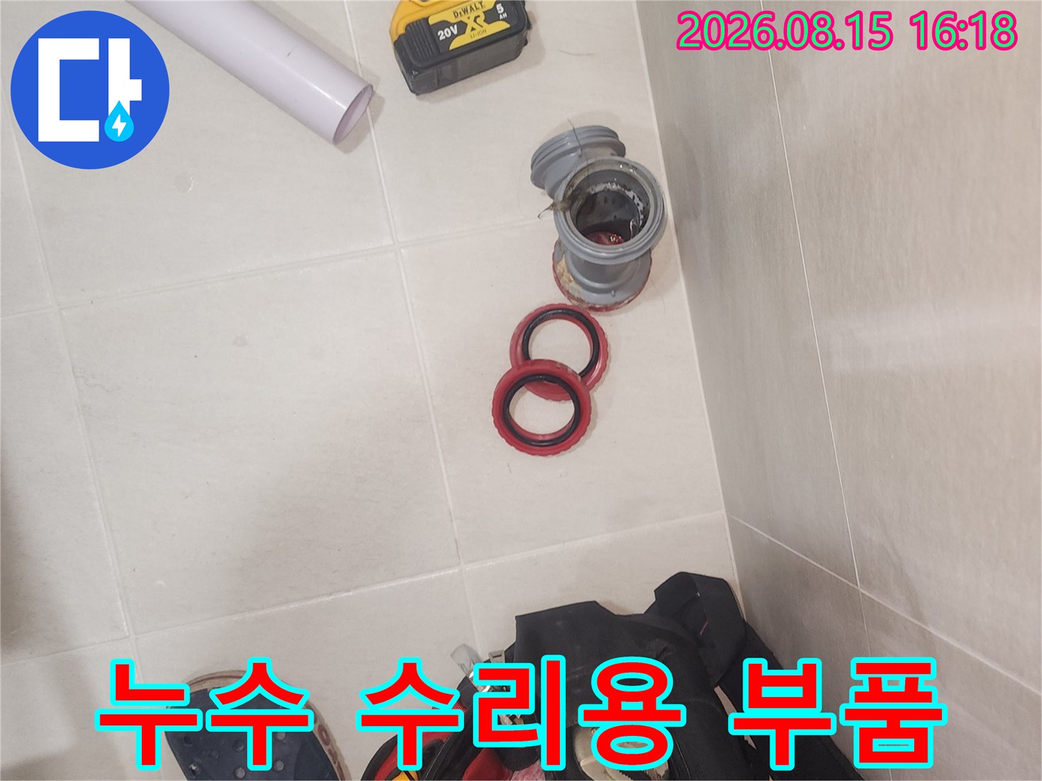 바닥에 놓인 하수도 연결 부속과 고무 패킹 및 작업용 드릴