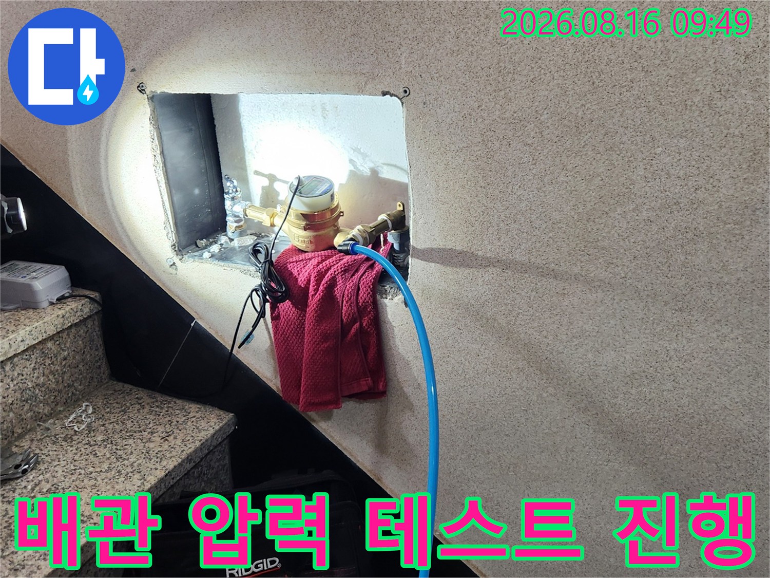 개방된 벽면 내부 배관에 압력계를 연결하여 누수를 점검하고 있습니다.
