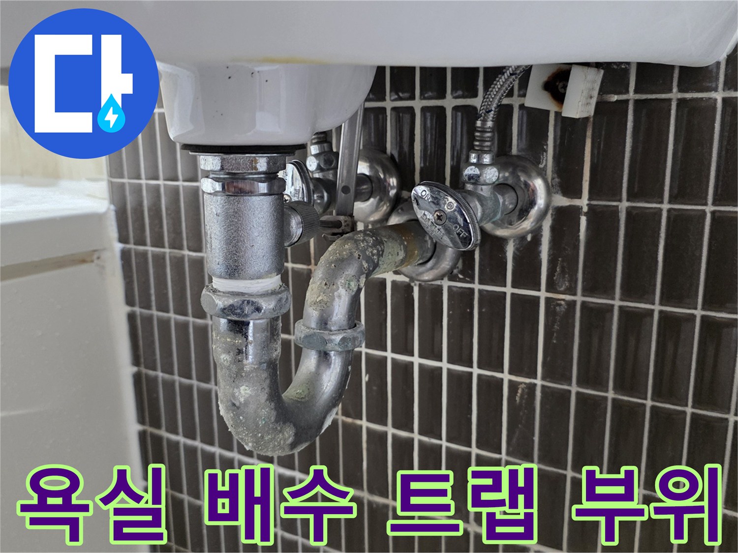 세면대-배수관-연결부와-벽면-타일의-근접-사진