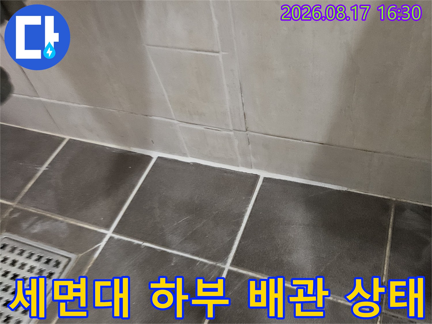 욕실 바닥-어두운 타일과 세면대 금속 배관 연결 부위