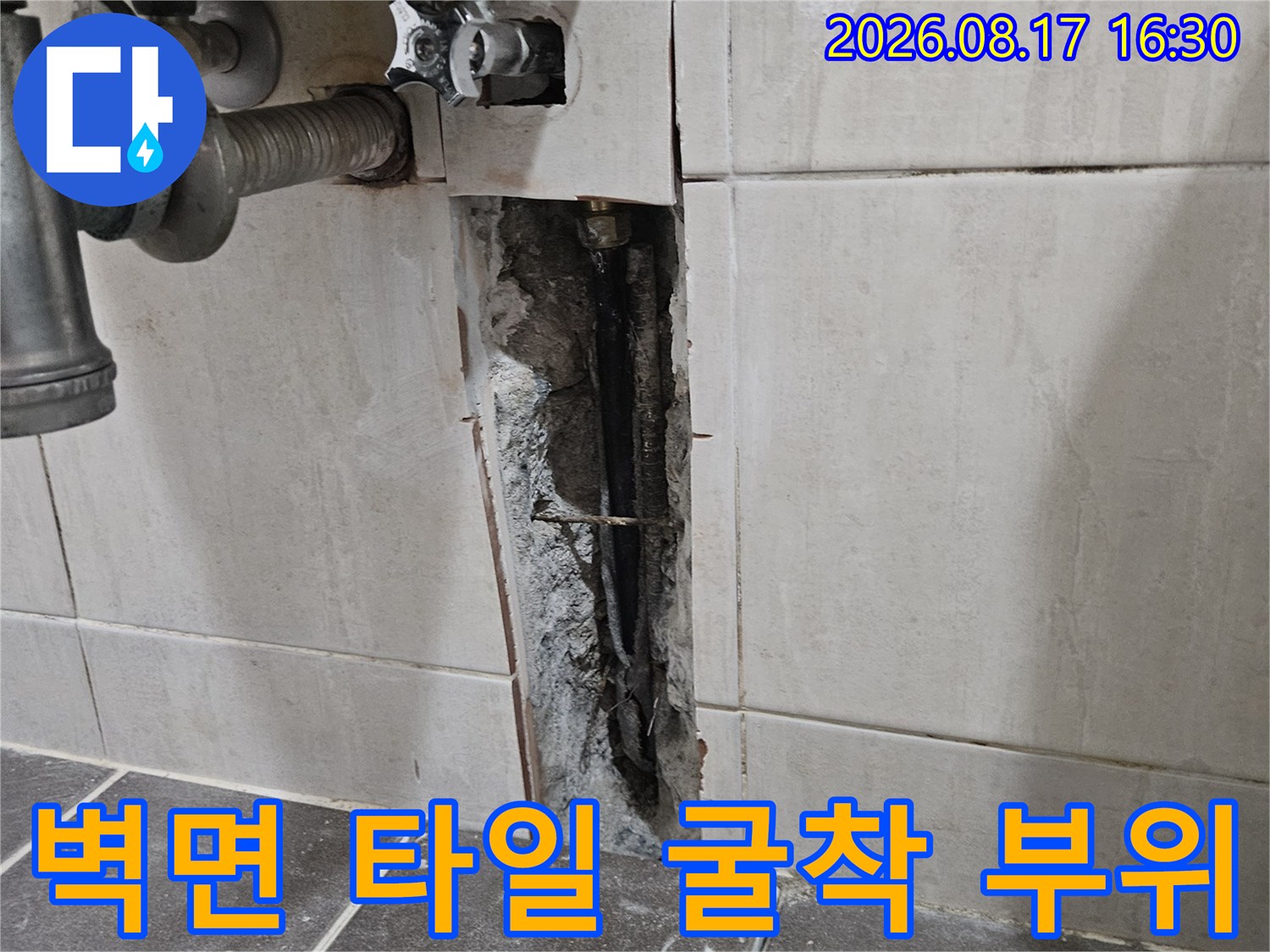 타일이 제거되어 내부 배관이 드러난 세면대 하부 벽면
