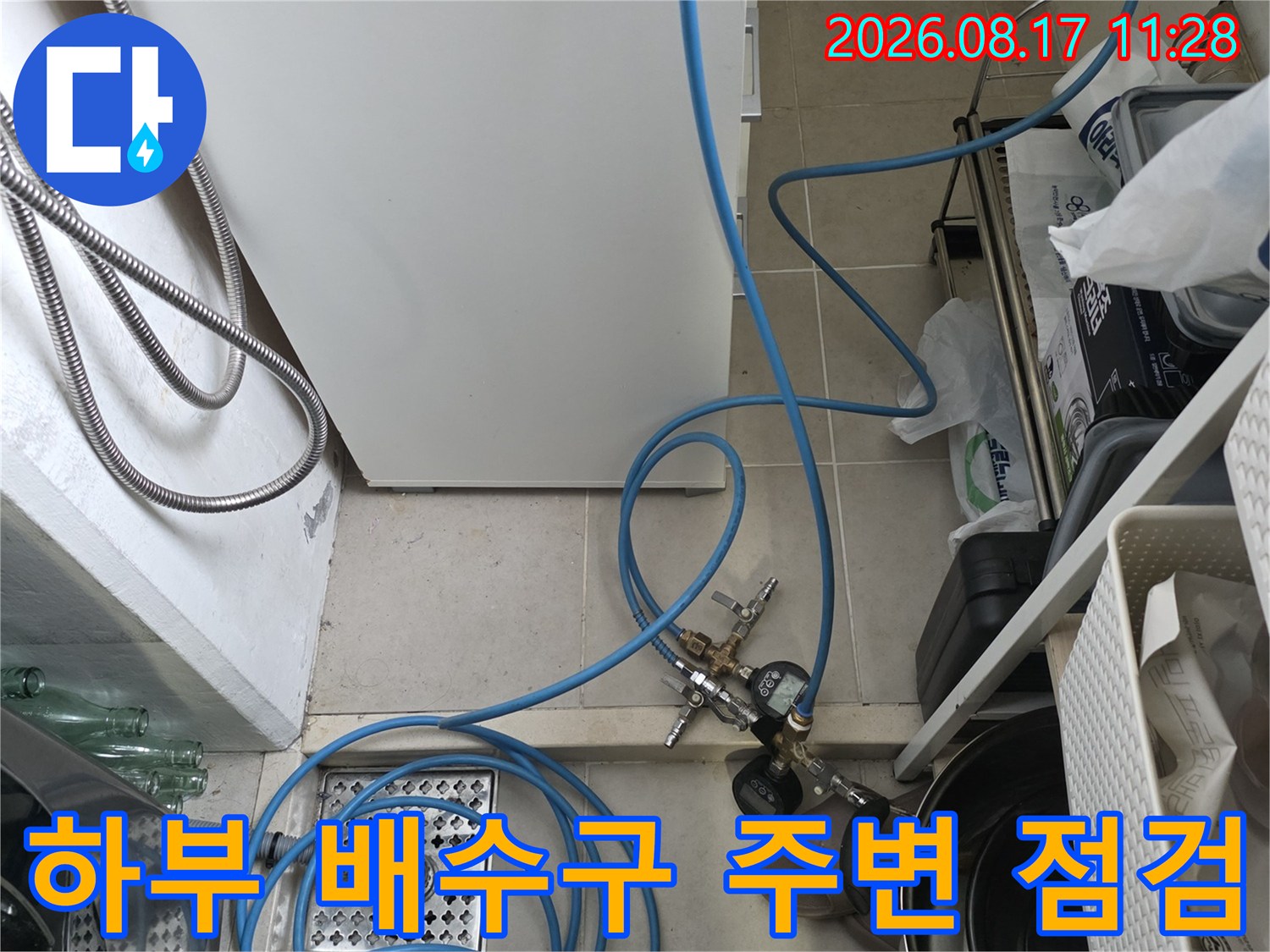 싱크대 아래 배수구와 복잡하게 얽힌 배관 및 검사 장비