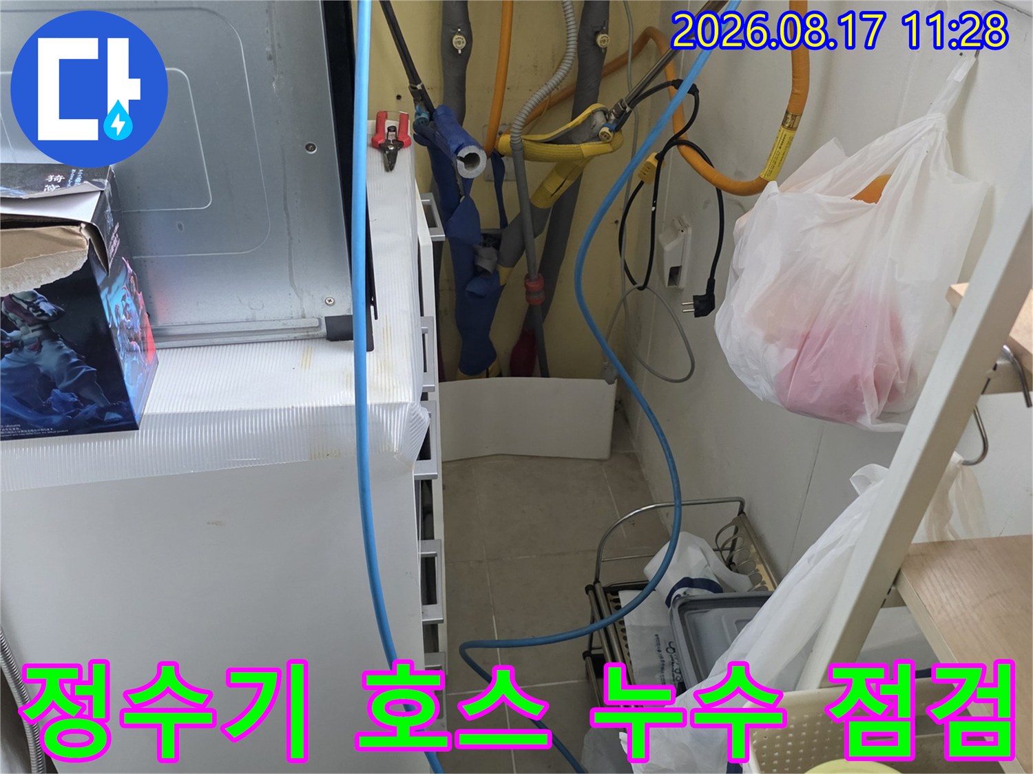 싱크대 아래 정수기 연결 호스와 수도 배관의 연결 상태를 면밀히 관찰하는 장면입니다.