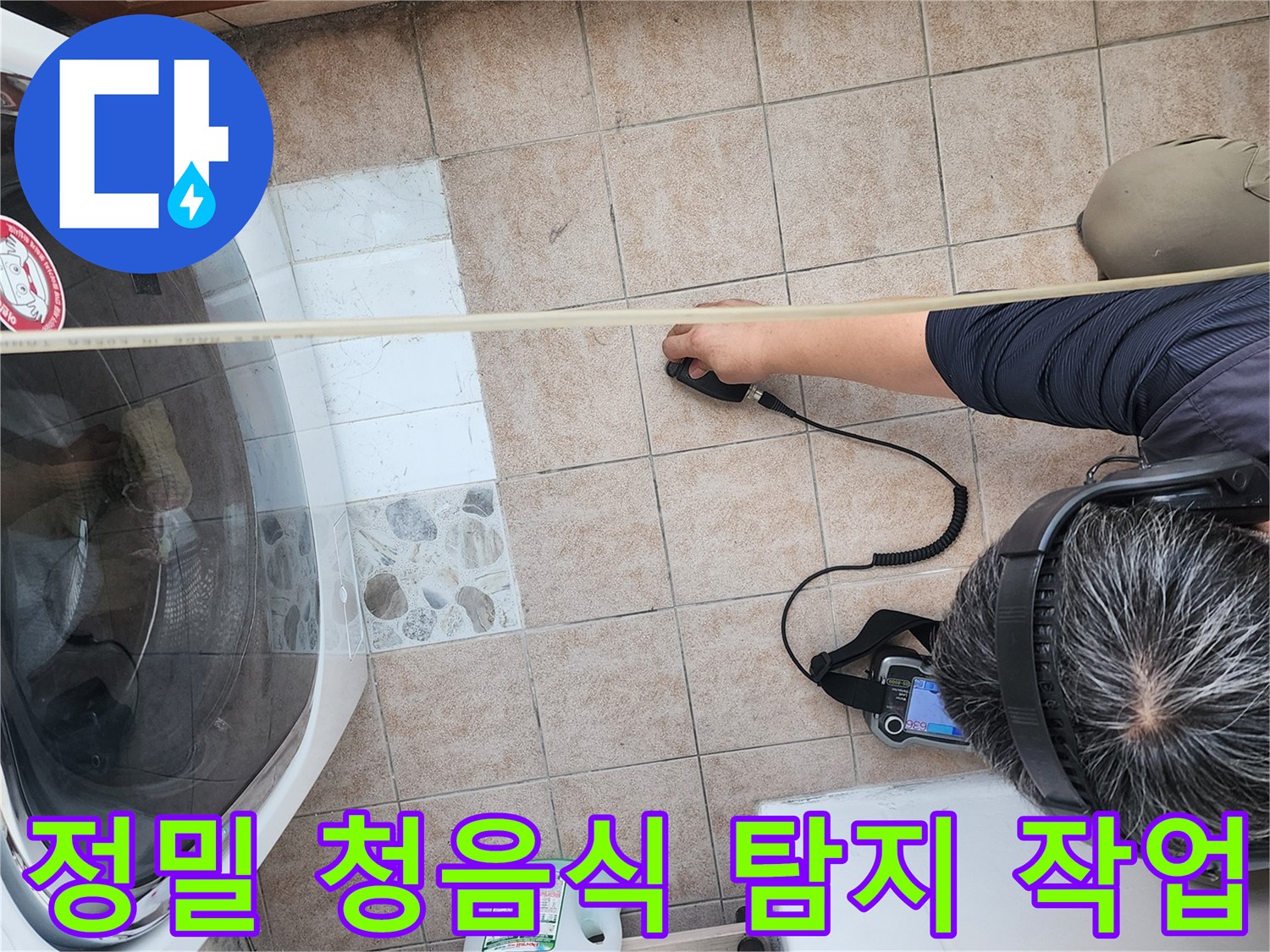 세탁기 주변 바닥 면에서 누수 지점을 찾기 위해 집중하고 있는 엔지니어