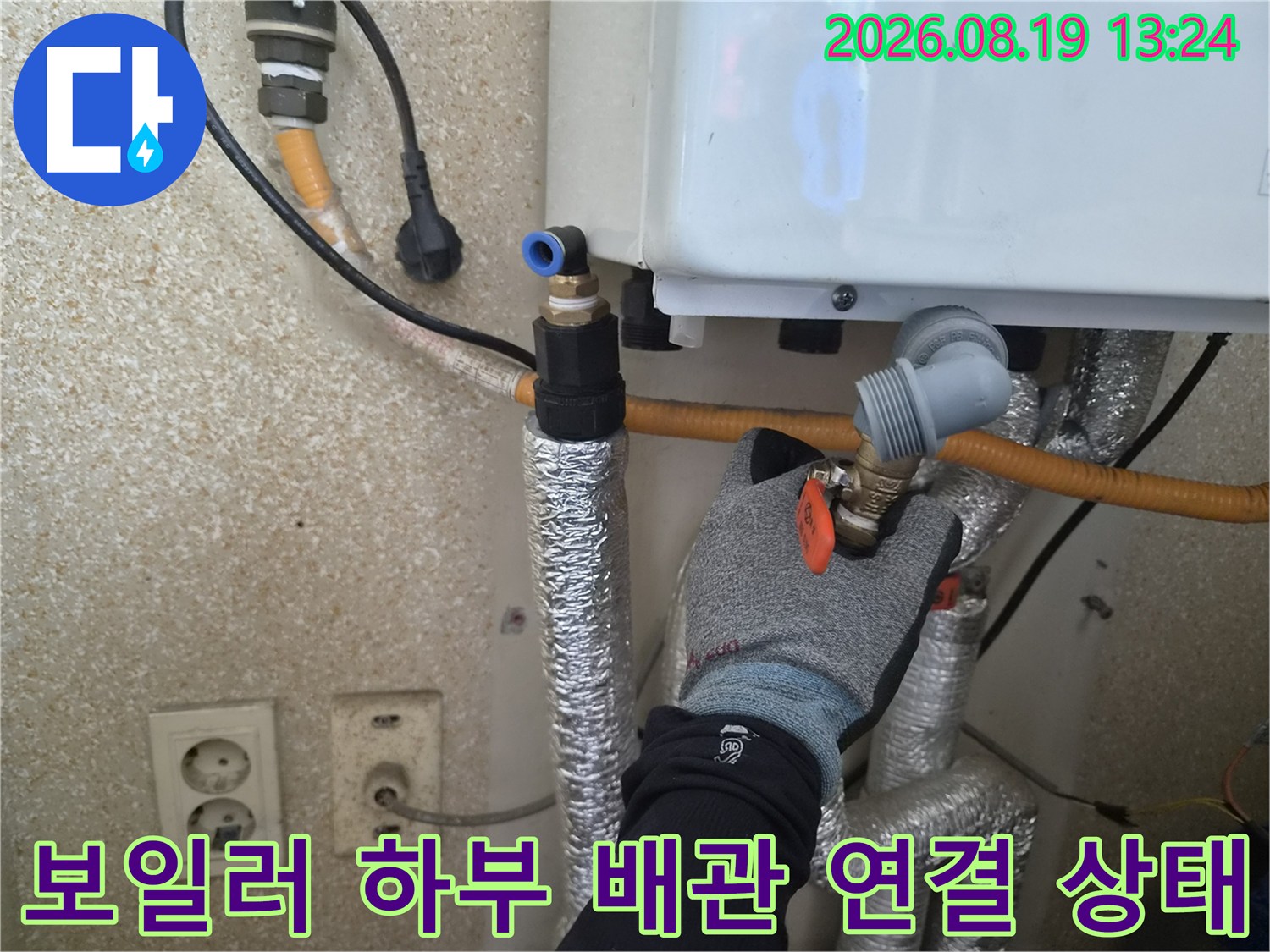 은색 보온재가 씌워진 배관과 주황색 밸브의 연결 부위를 촬영했습니다.