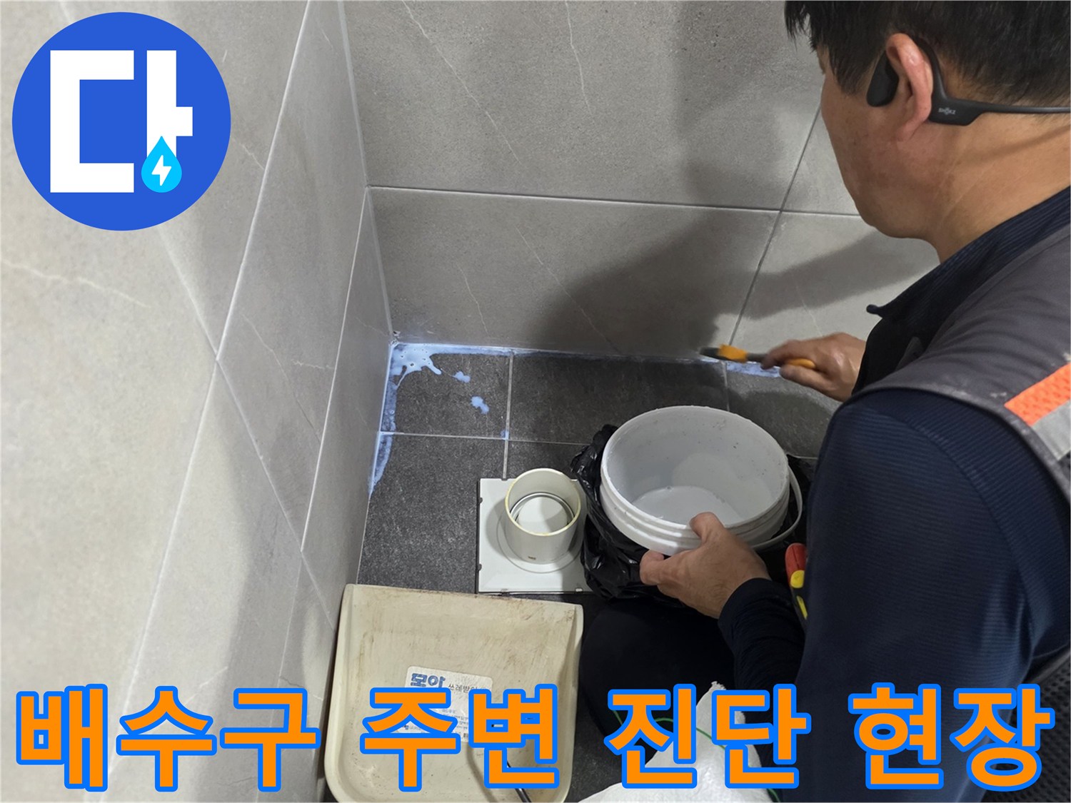 화장실 유가 주변의 젖은 타일 상태와 작업 장비를 보여주는 사진입니다
