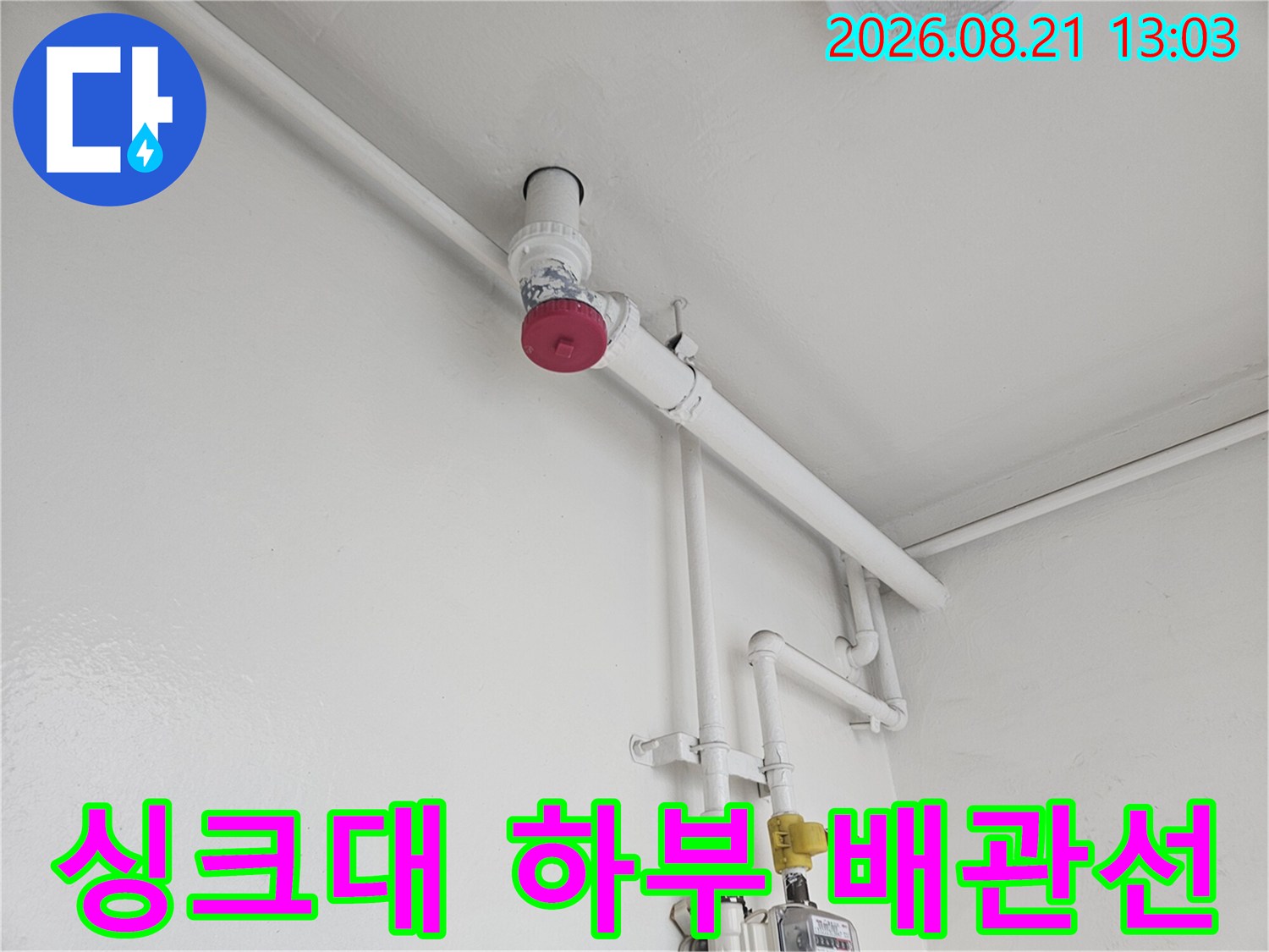 하얀 벽체에 설치된 수도 계량기와 연결 파이프들의 근접 촬영입니다.