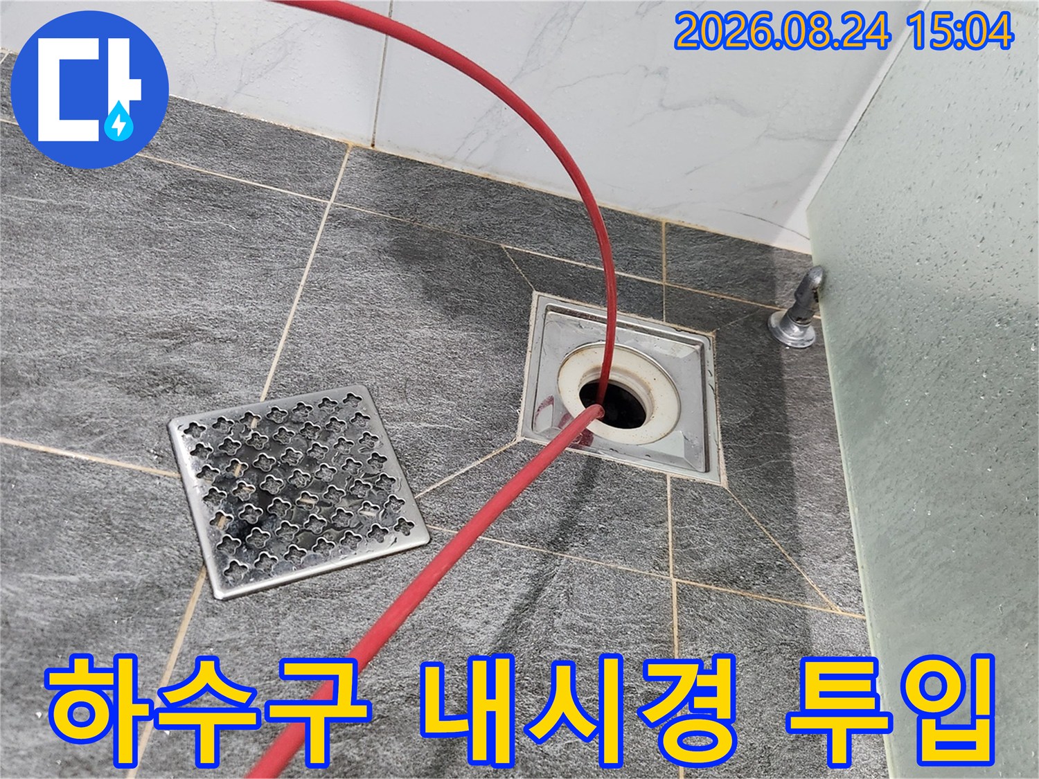 배수구 덮개 옆-열려있는 배수관 내부로 점검용 케이블을 진입시킨 모습입니다.