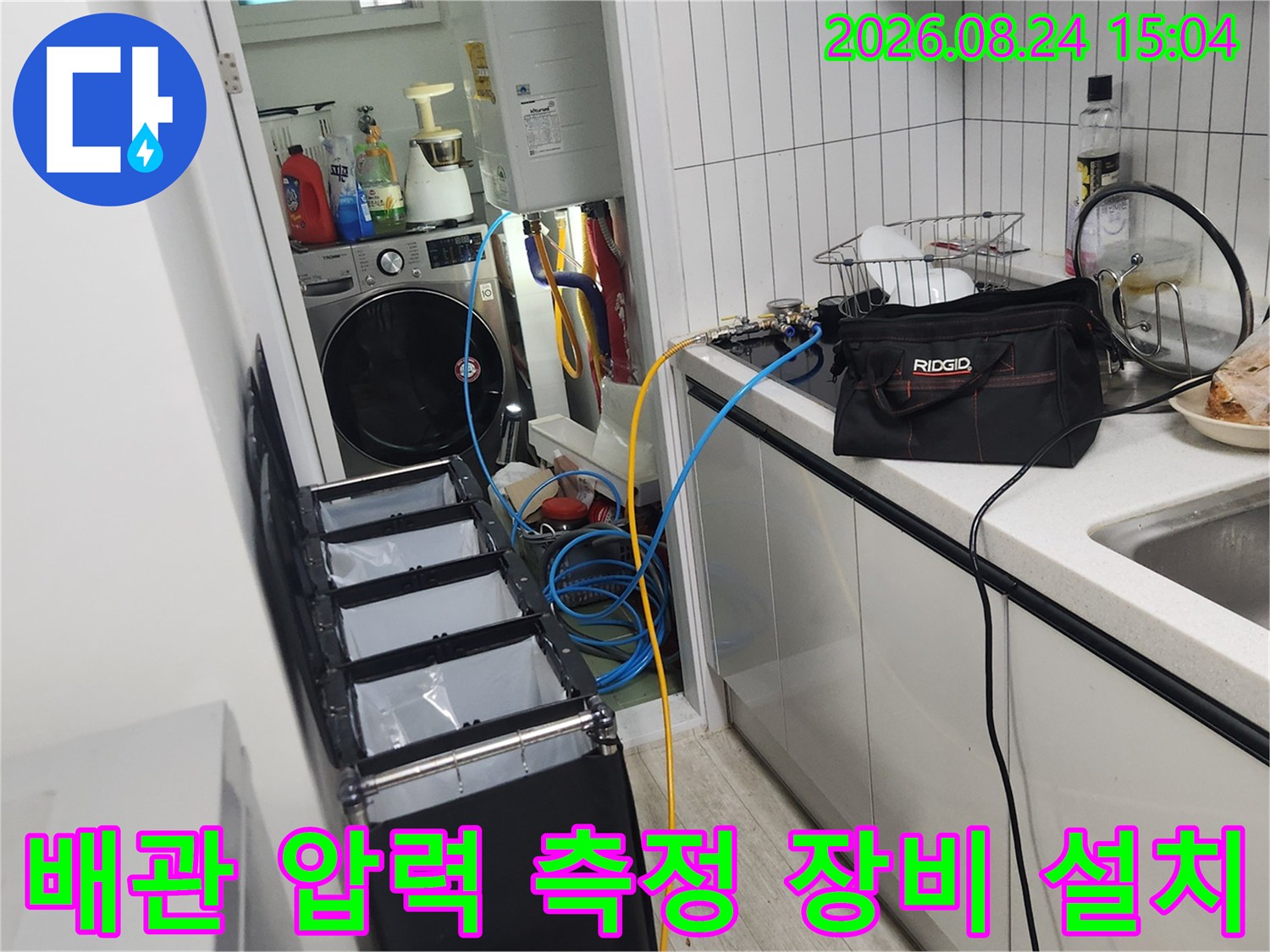 세탁기와 보일러 배관이 모인 곳에서 공압 검사를 위해 장비를 연결한 모습입니다.