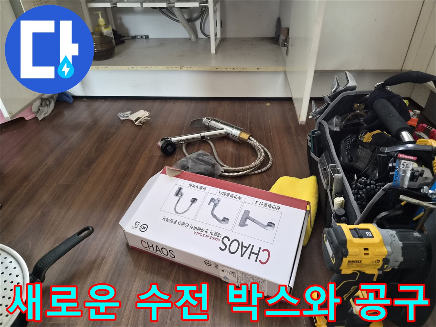 주방 싱크대 하부장에 놓인 새 수전 제품 상자와 전동 드릴 작업 도구