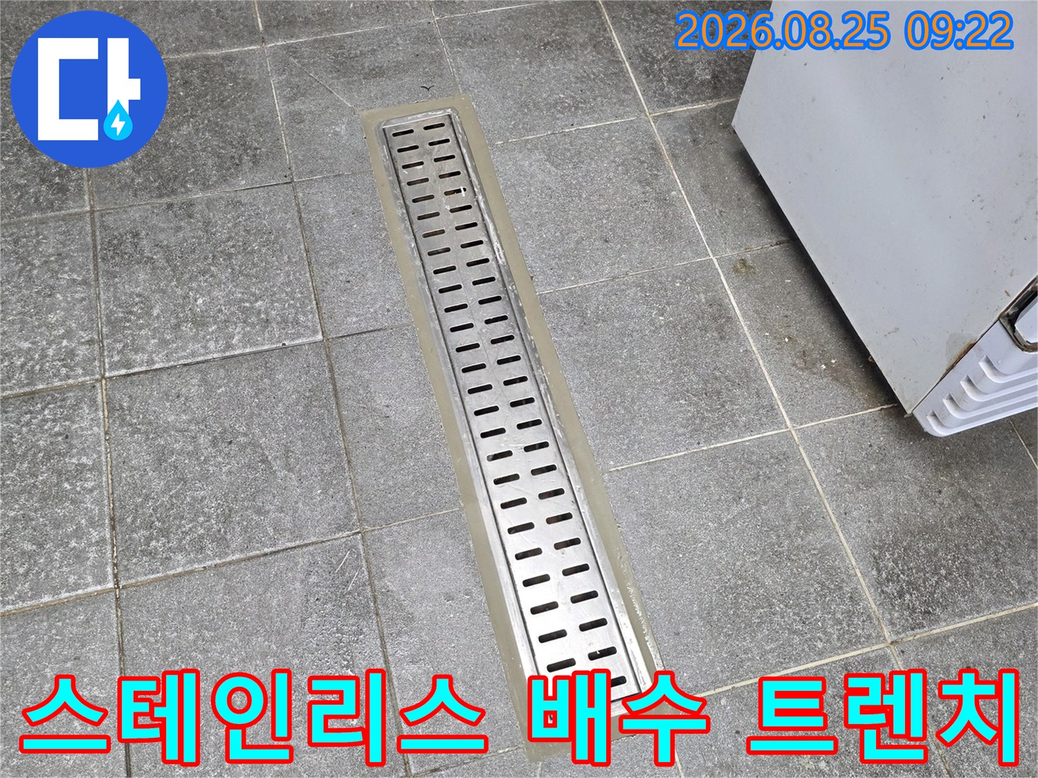 회색 타일과 스테인리스 배수구가 만나는 지점의 근접 사진입니다.
