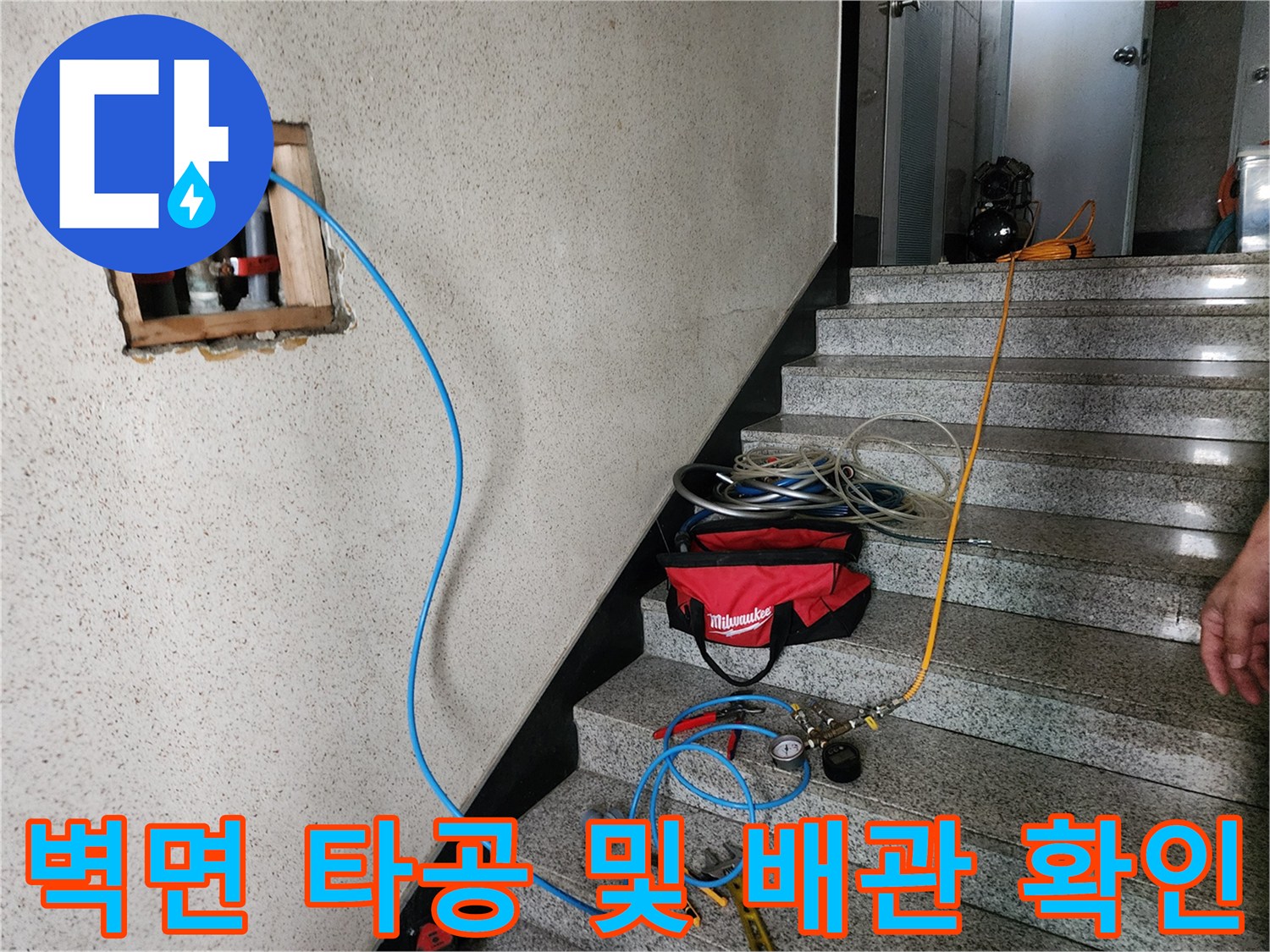 타공된 벽 내부의 배관과 연결된 파란색 호스 상세