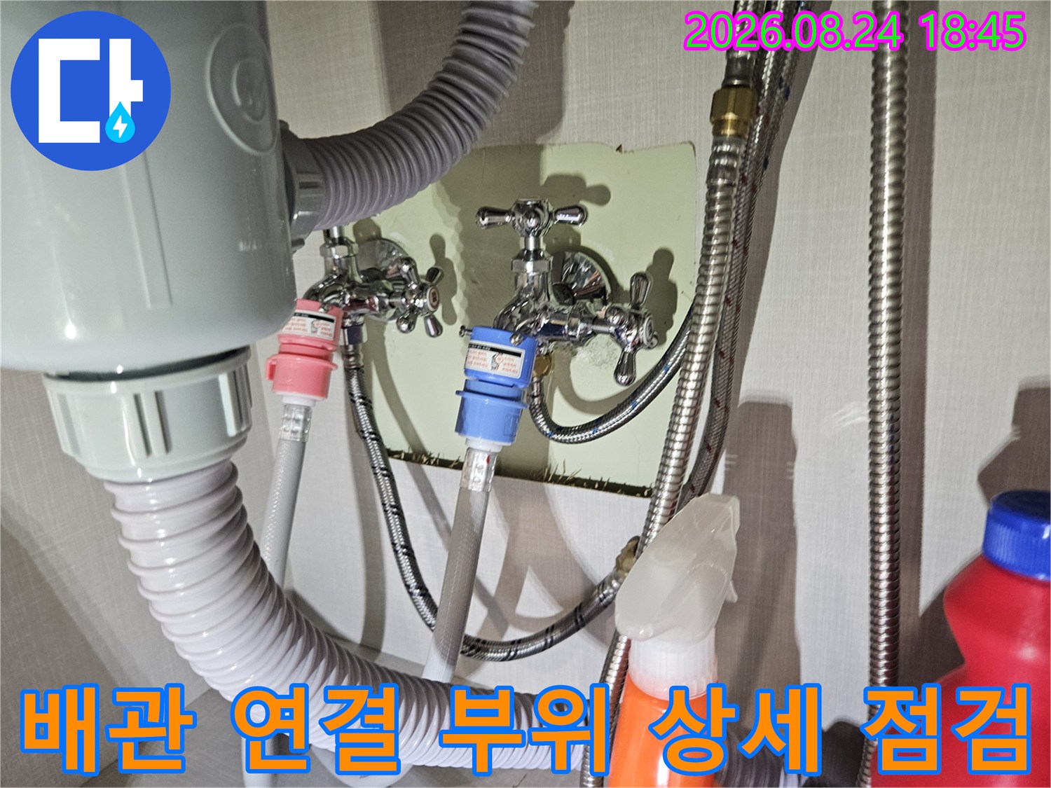 세탁실 벽면의 수도 수전과 알록달록한 호스들이 연결된 배관 설비 모습