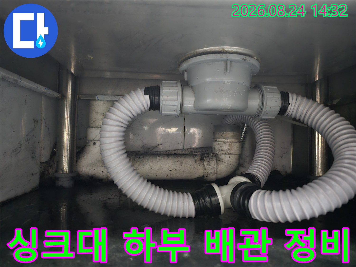 깨끗하게 정리된 싱크대 아래쪽의 배수 호스 및 연결 소켓 상세 사진입니다.