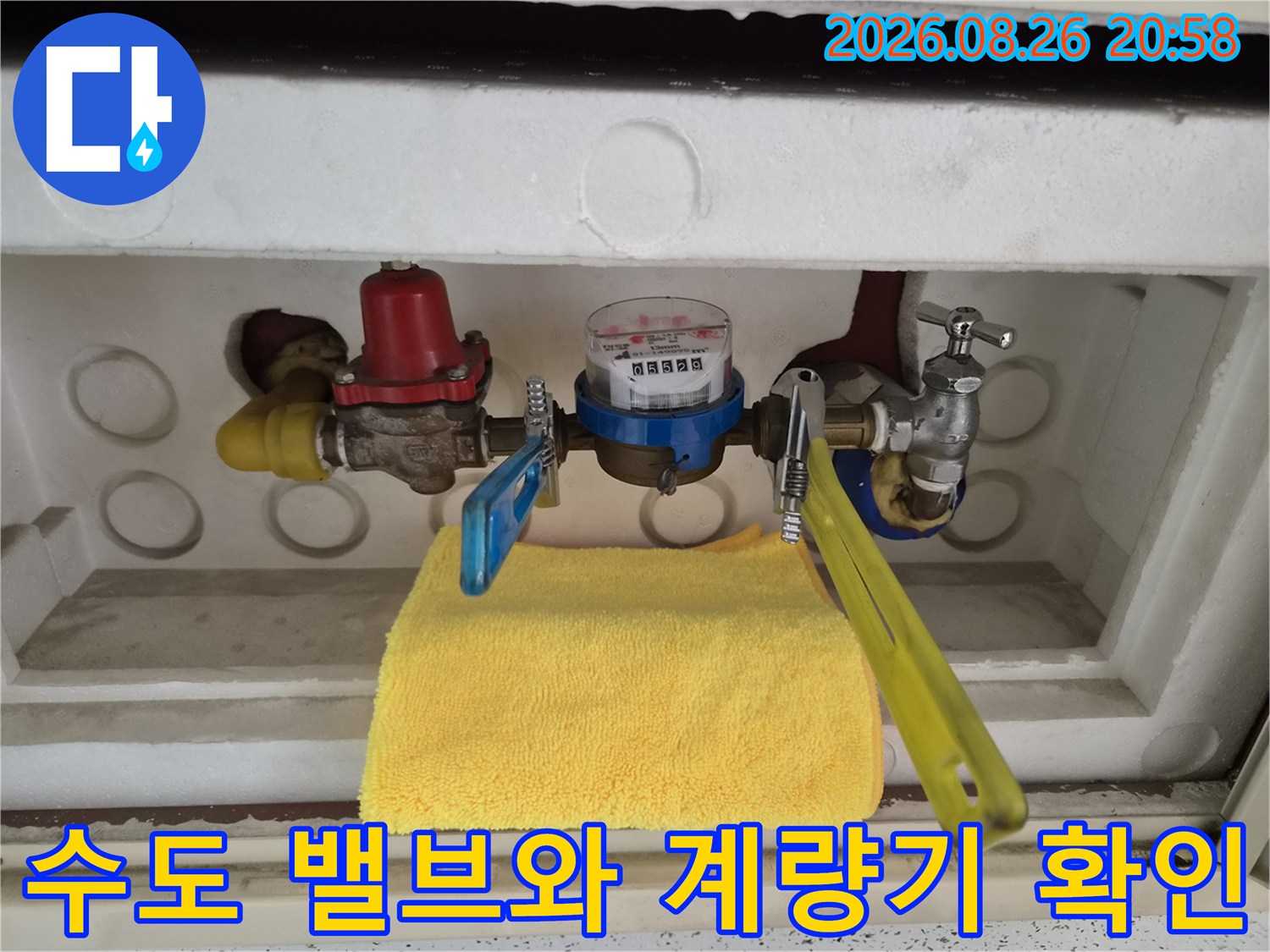 금속 배관과 파란색 핸들 밸브가 포함된 수도 계량기 내부입니다.