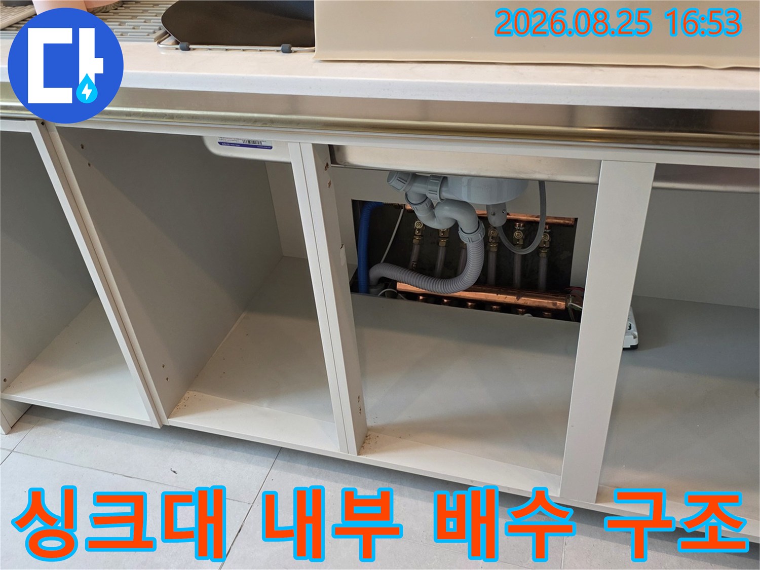 싱크대 하부장 내부에 노출된 배수 호스와 연결 부위의 모습입니다.