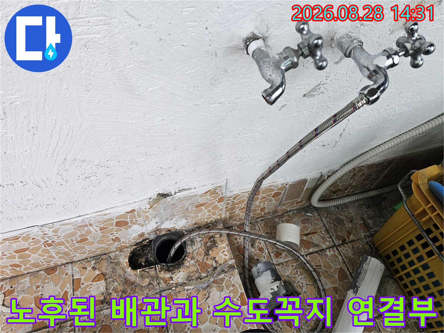 세탁실 벽면에 설치된 두 개의 수도꼭지와 바닥으로 이어지는 배수 호스 상태입니다.
