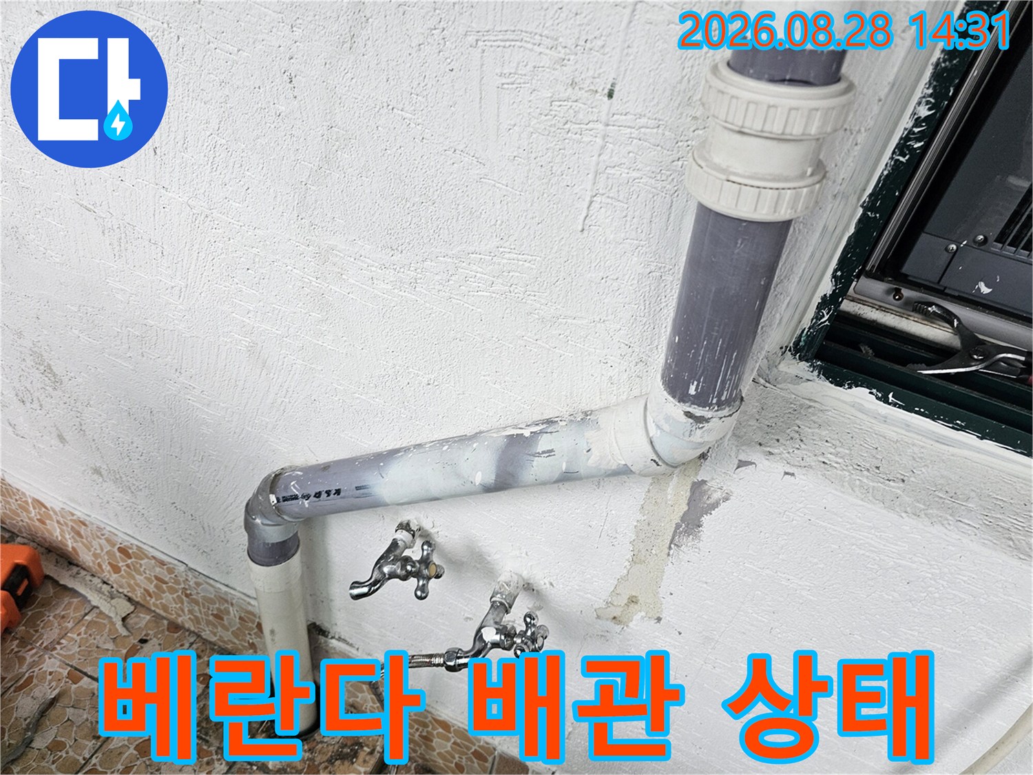 흰색 벽면의 회색 배수관과 금속 수도꼭지 연결 부위 상세 사진