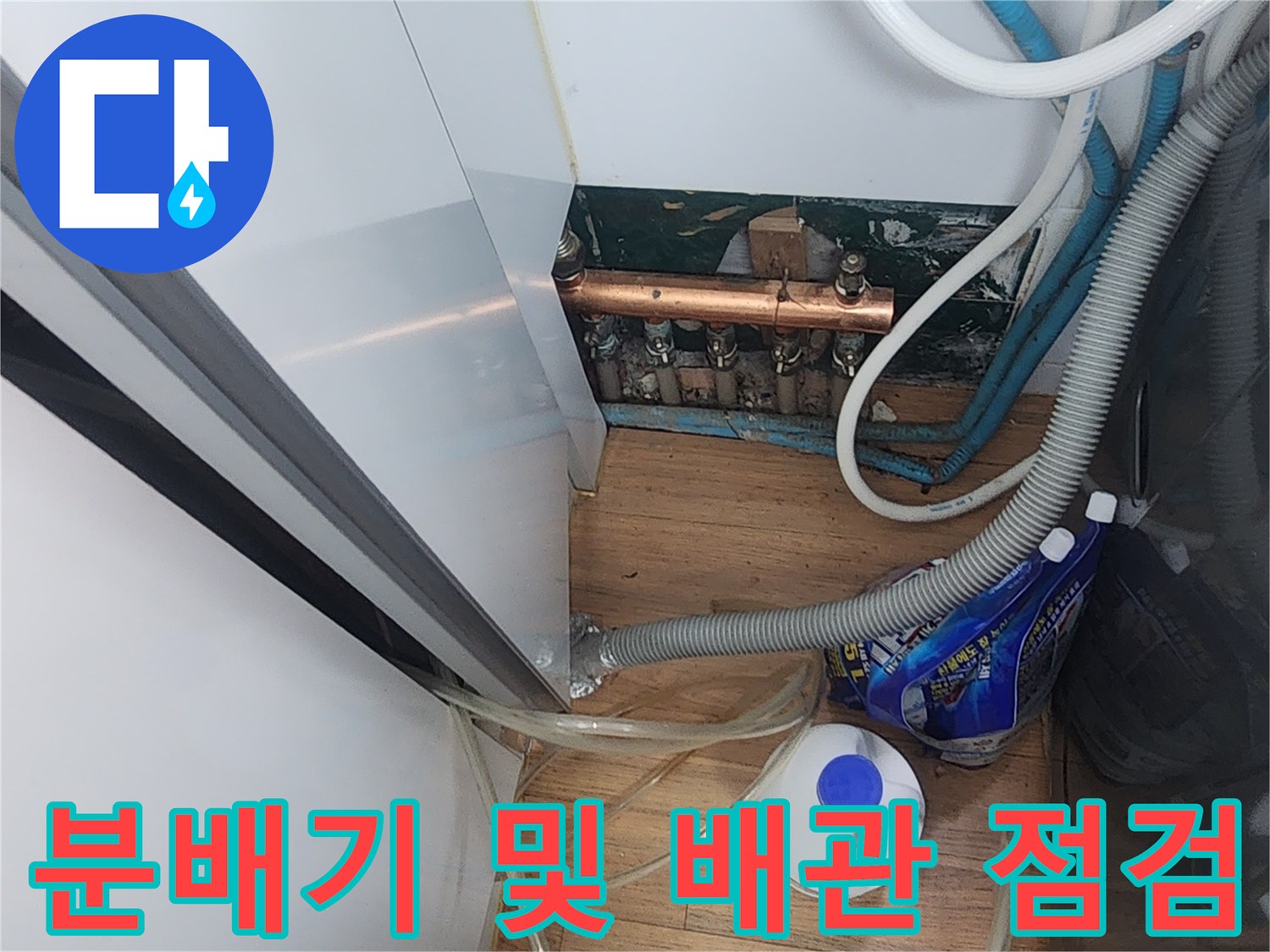 보일러실 내 금속 분배기와 연결된 투명 호스들의 근접 모습