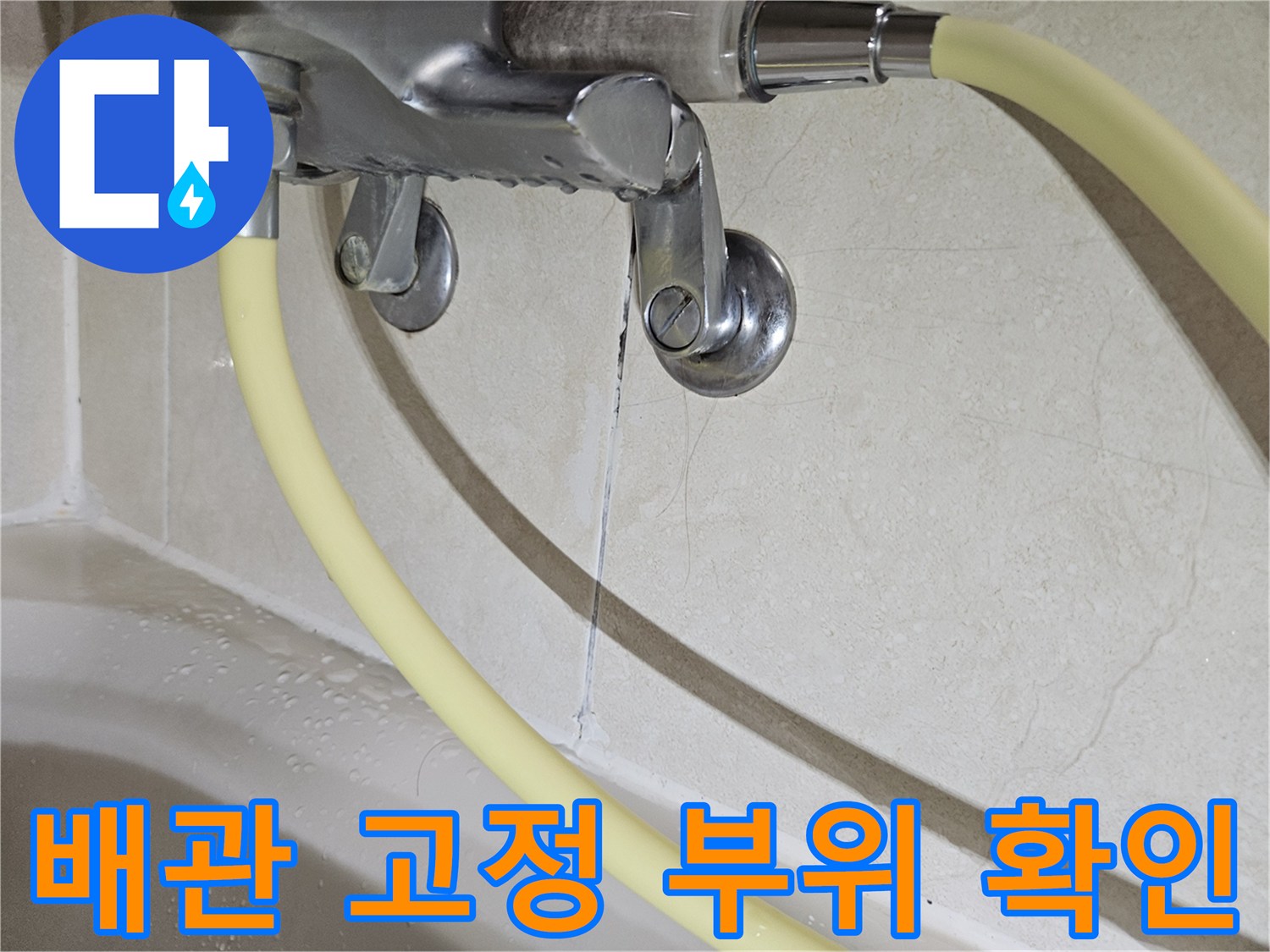 벽면에 설치된 배관 고정 장치와 주변 타일의 균열 상태입니다.
