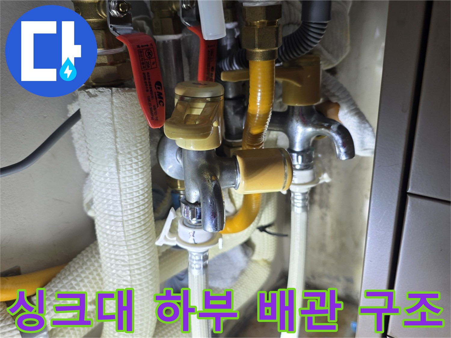 노란색 보온재와 수도 밸브가 포함된 싱크대 아래 배관 시설