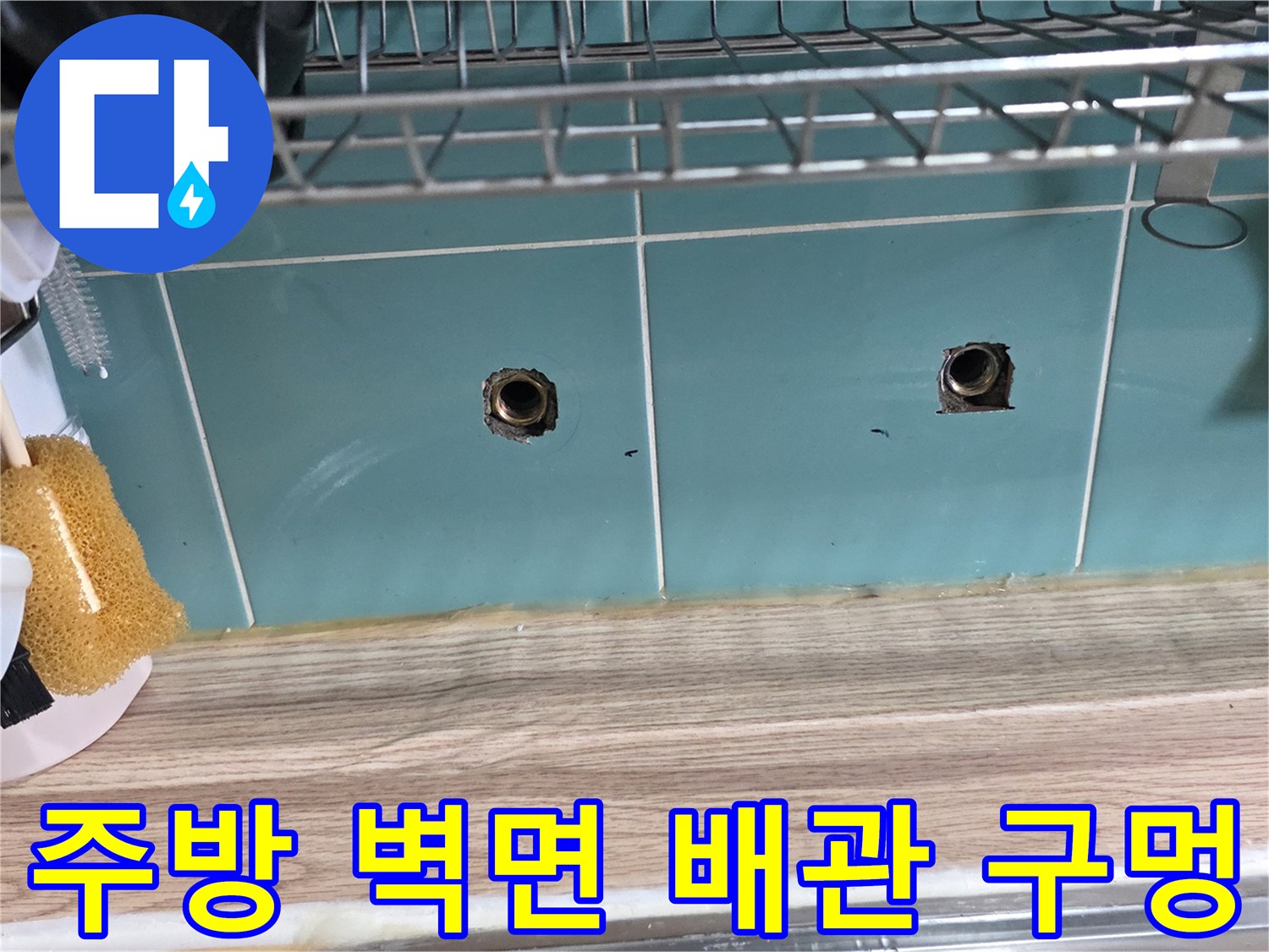 싱크대 하부 타일 벽면에 위치한 수도 배관 입구 모습