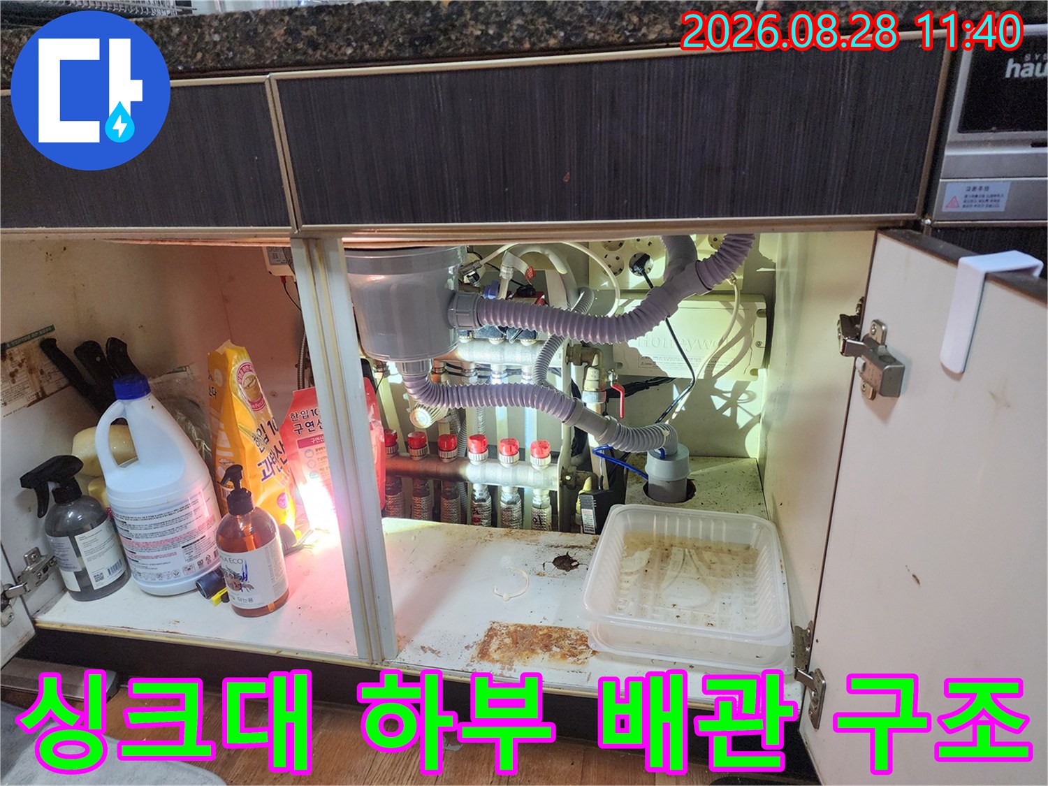 복잡하게 연결된 싱크대 하단 배관과 에어컨 드레인 호스의 배치 상태