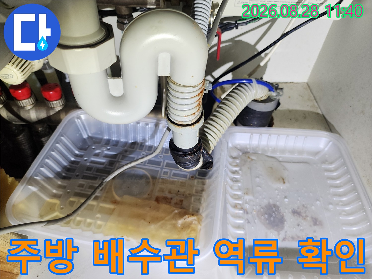 싱크대 하부 배관 연결 부위에서 물이 새어 나와 대야에 고여 있는 장면입니다.