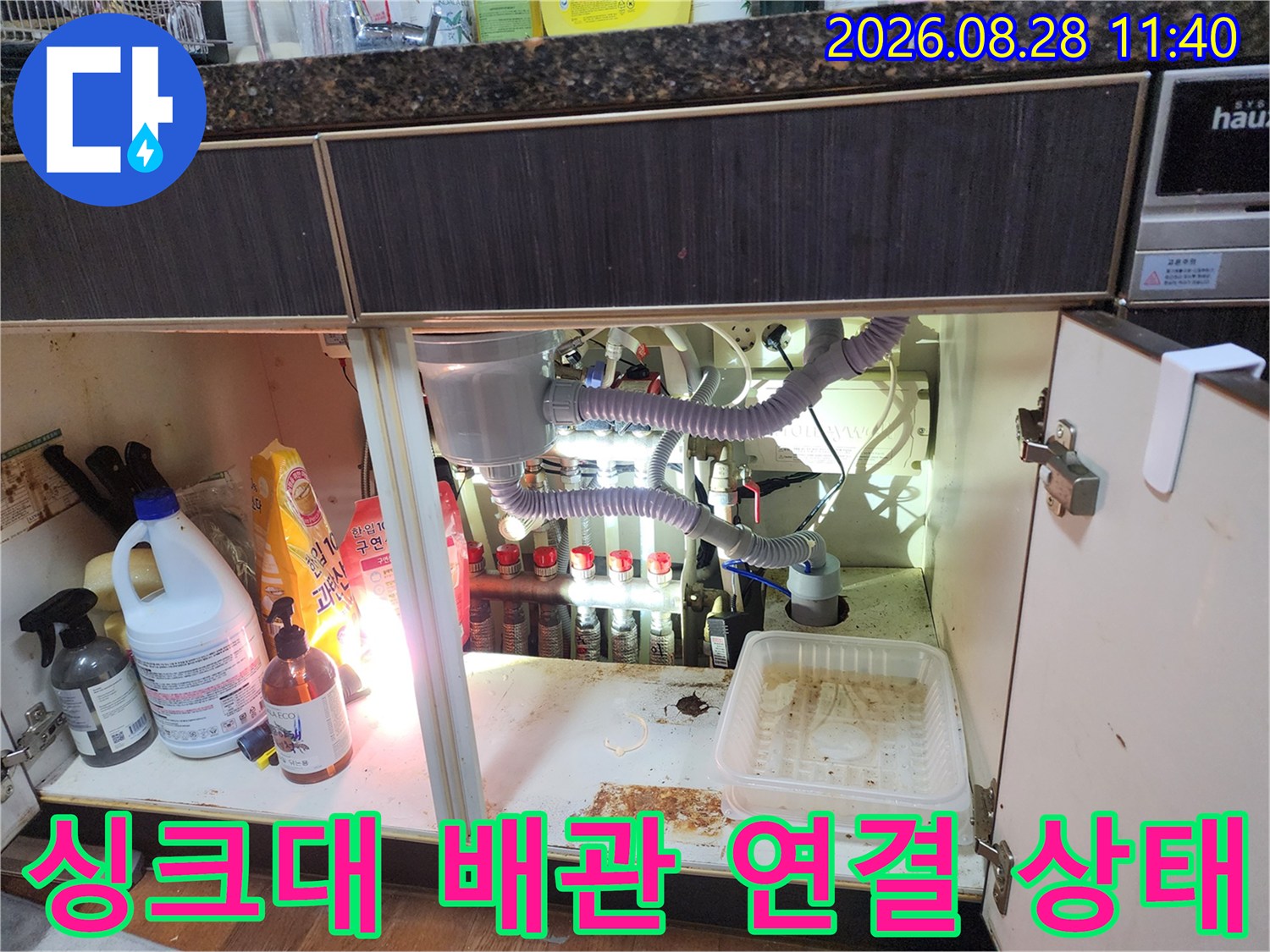 싱크대 하부장 내부의 드레인 호스와 여러 가지 배관들이 연결된 모습