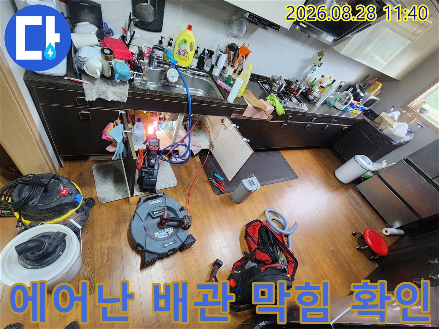 에어컨 드레인 호스와 싱크대 배관의 연결 상태를 점검하는 현장 사진입니다.