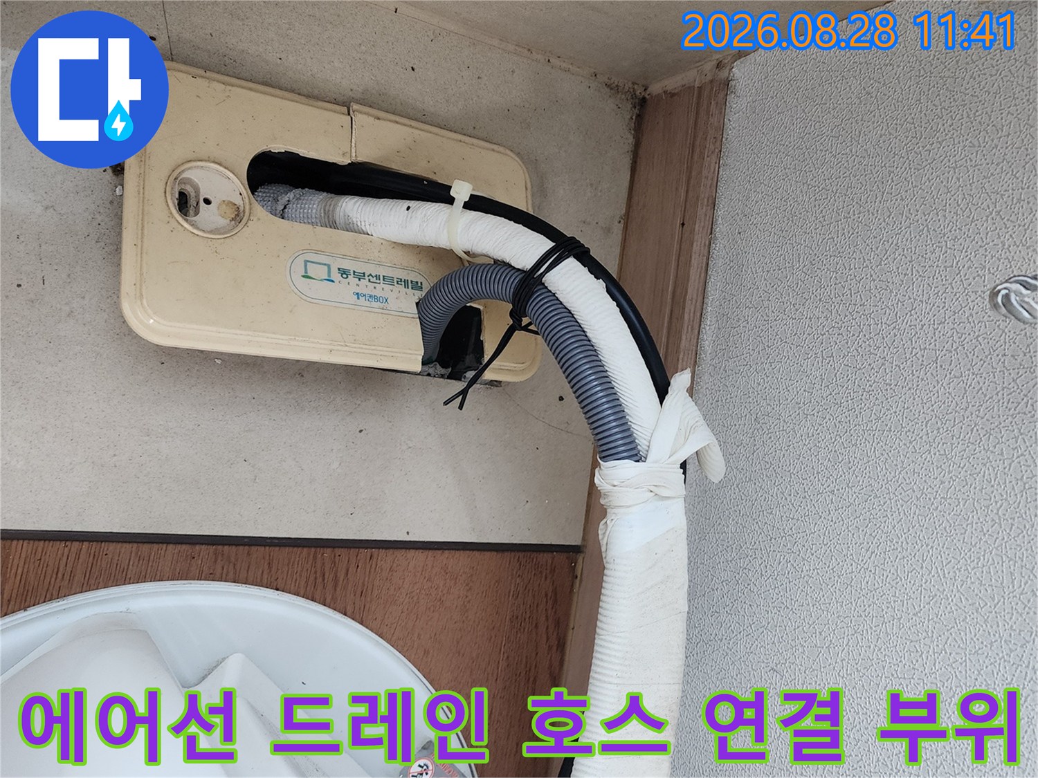 하얀색 보온재와-회색 주름관이 연결된 에어컨 배수관 모습