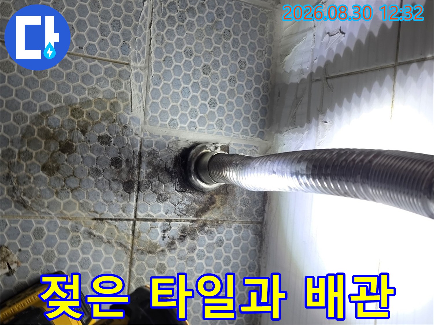 배관 주변 타일의 젖은 부위와 누수 흔적을 촬영한 사진