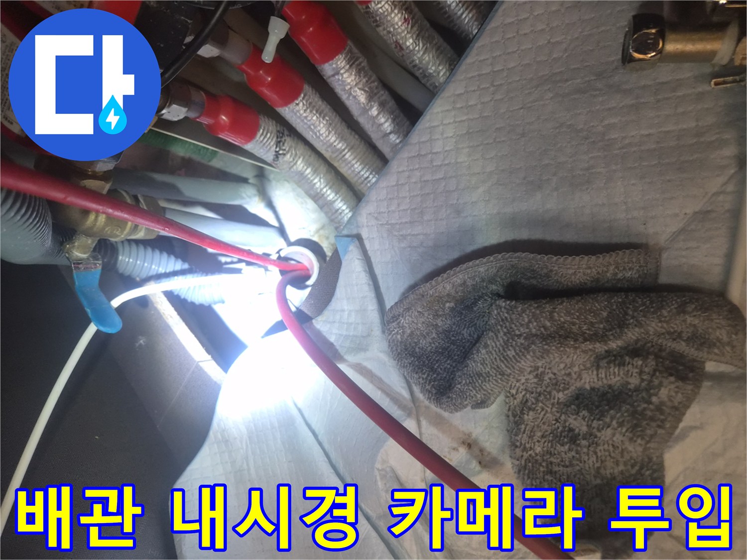 싱크대 밑 복잡한 배관 구조 사이로 내시경 장비를 진입시키는 작업 모습입니다.