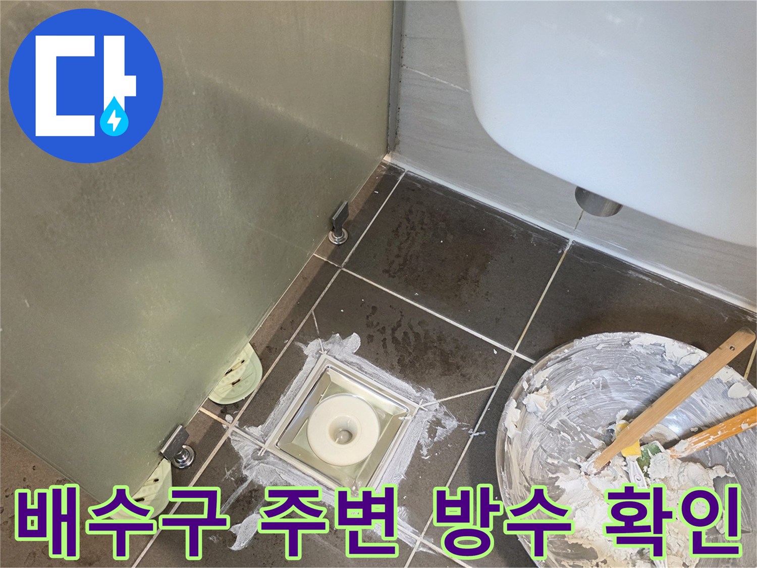 화장실 배수구 유가 주변의 타일 틈새와 물기 흔적을 점검하는 모습