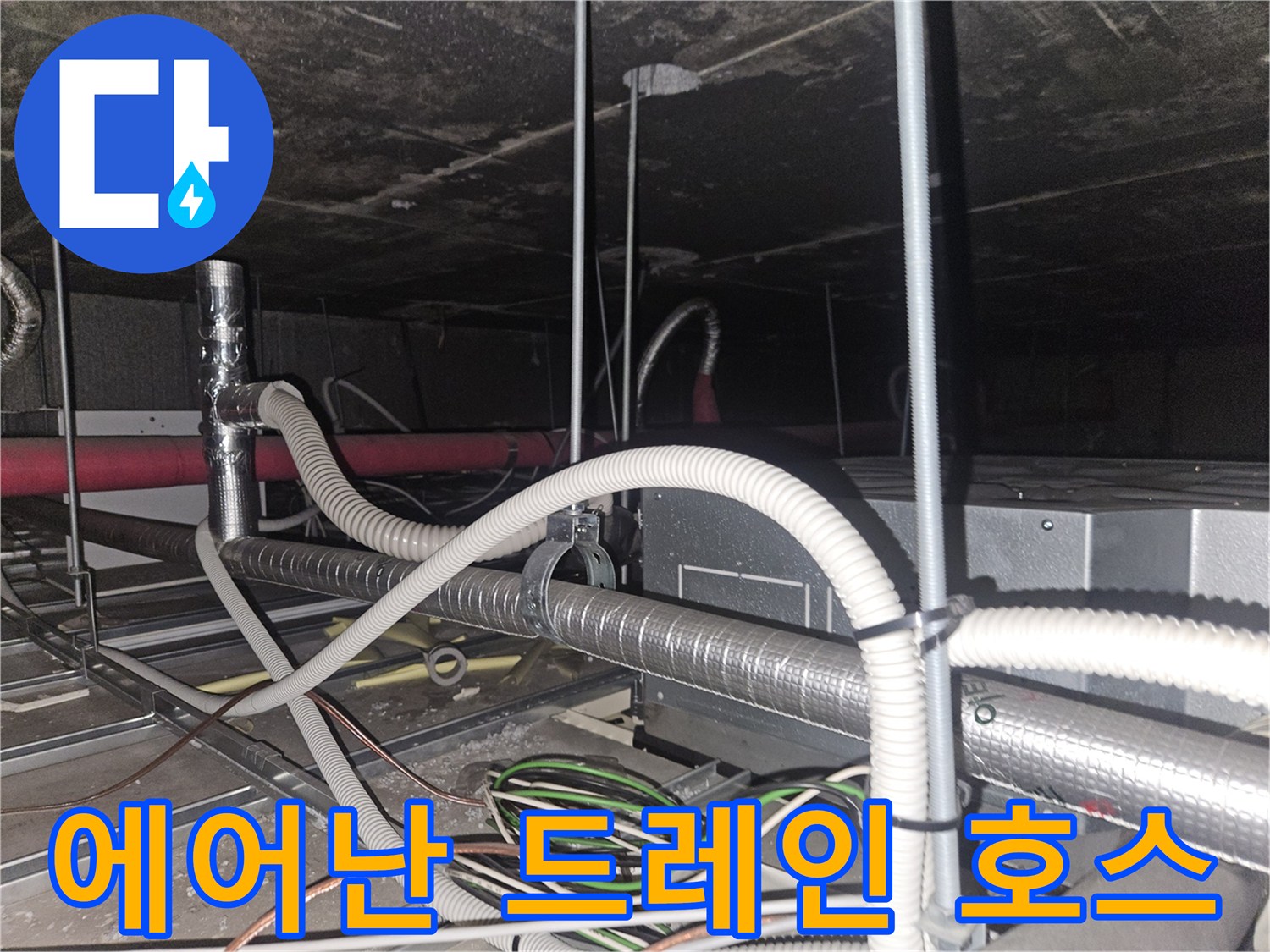 천장 내부의 흰색 드레인 호스와 금속 배관이 교차하는 지점
