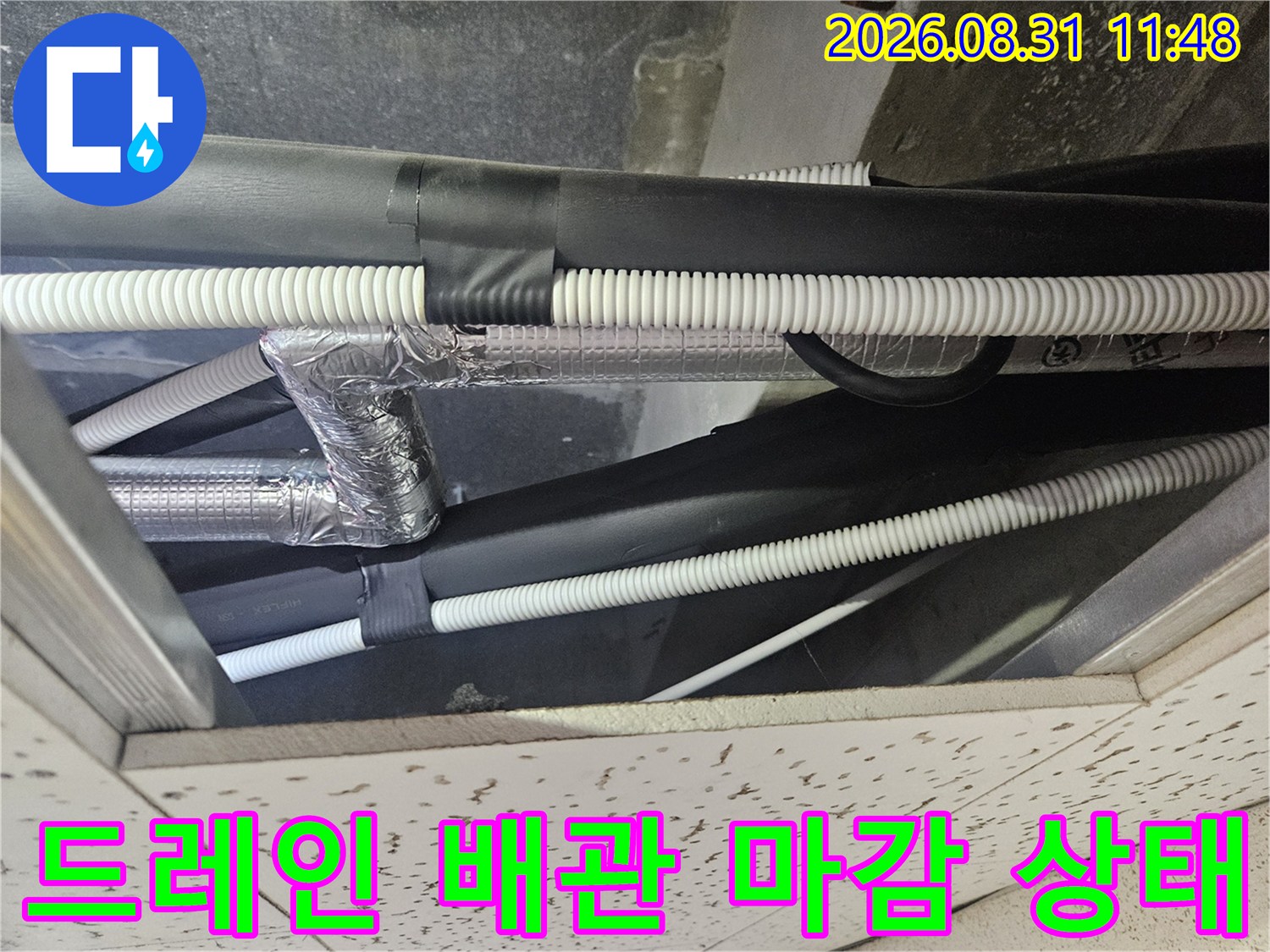 천장 텍스 사이로 보이는 에어컨 드레인 호스와 보온재 처리된 배관입니다.