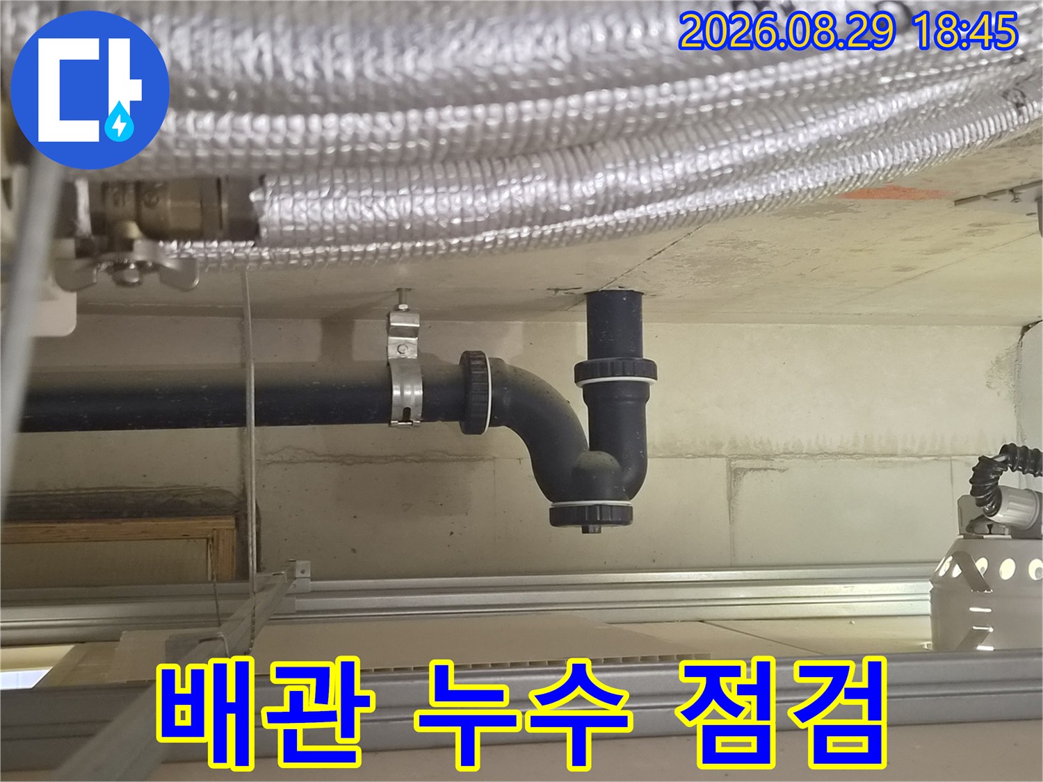 아파트 천장 내부의 은색 보온재 배관과 검은색 하수 배관 연결 모습입니다.