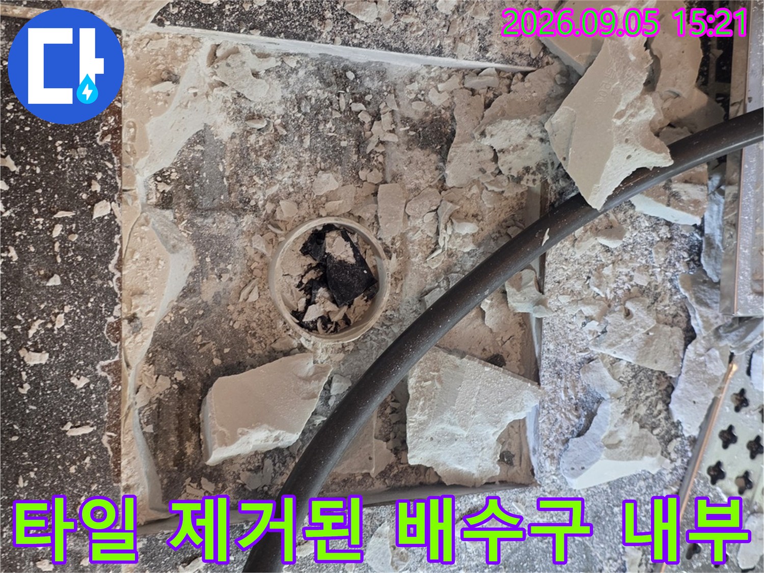 유가 주변 타일을 걷어내고 배수관 연결부를 노출시킨 공사 현장 사진입니다.