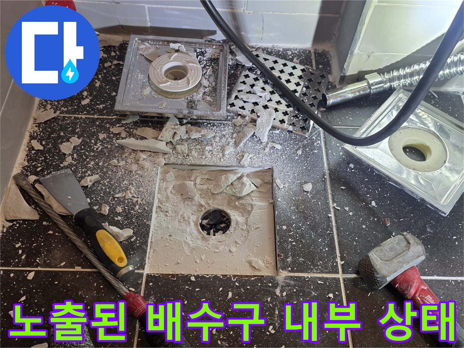파손된-타일-사이로-드러난-배수관-연결-부위의-점검-장면