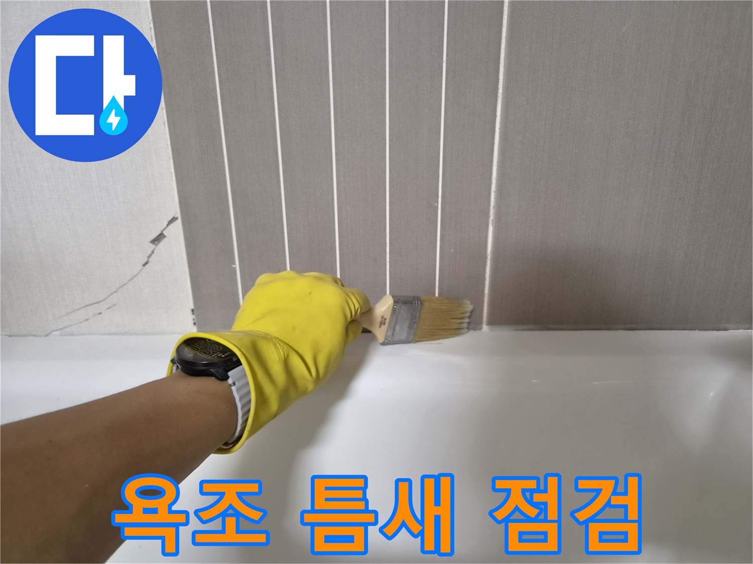 노란 장갑을 낀 작업자가 브러시로 욕조와 벽면 사이를 살피는 모습
