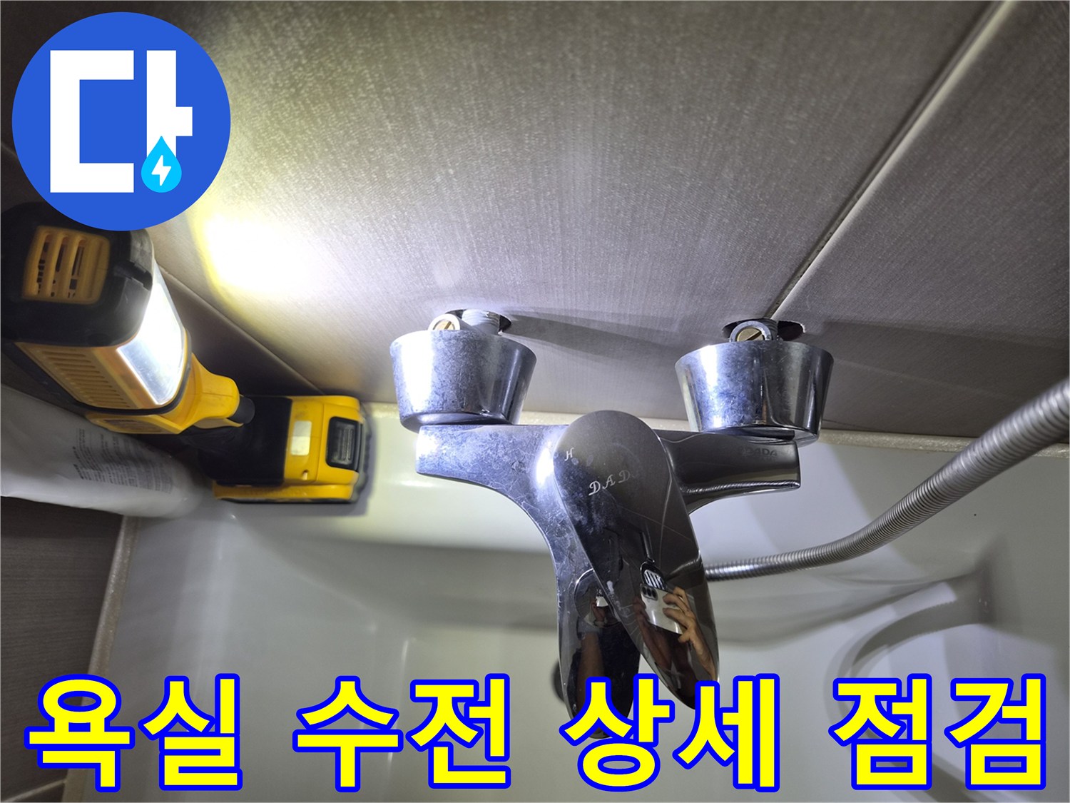 조명 아래 보이는 욕실 샤워기 수전과 금속 호스 부위